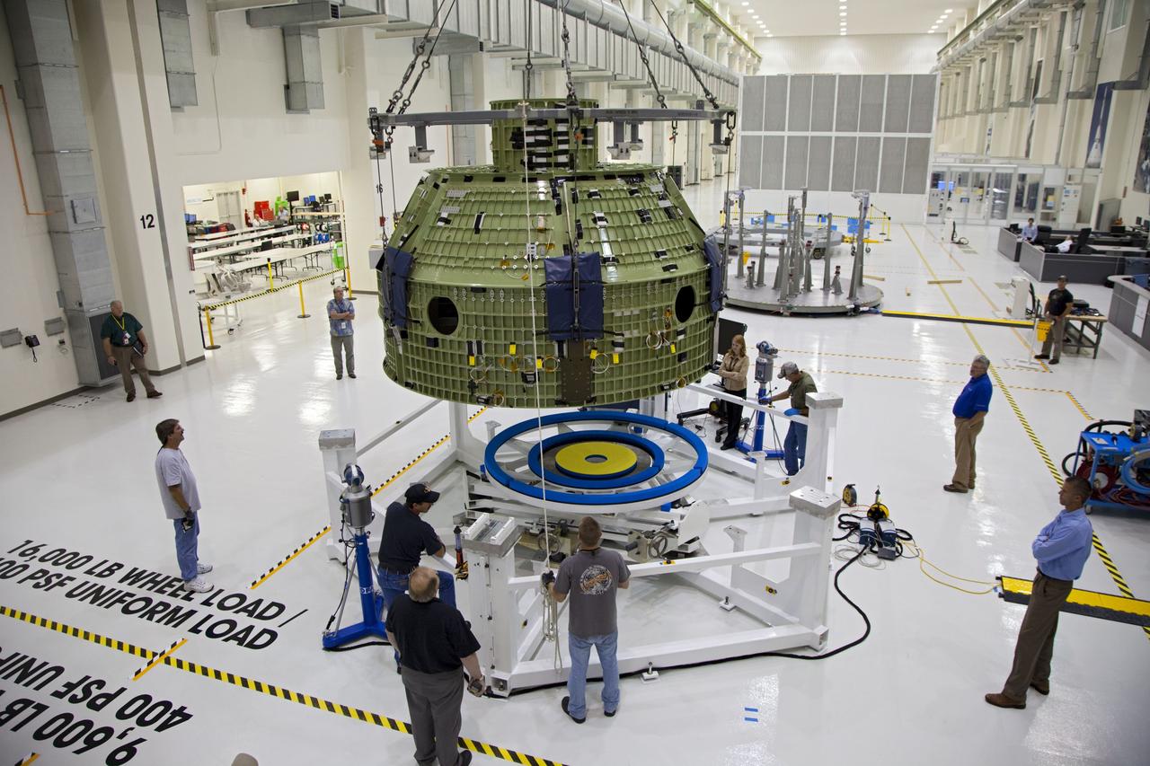 CAPE CANAVERAL, Fla. – Inside the Operations and Checkout Building at NASA’s Kennedy Space Center in Florida, technicians monitor the progress as a crane lowers the Orion Exploration Flight Test 1 crew module toward the base of a birdcage tool. The birdcage will be used to continue installation of external components in preparation for Orion’s first uncrewed test flight in 2014 atop a Delta IV rocket. Orion is the exploration spacecraft designed to carry crews to space beyond low Earth orbit. It will provide emergency abort capability, sustain the crew during the space travel and provide safe re-entry from deep space return velocities. A second uncrewed flight test is scheduled for 2017 on NASA’s Space Launch System rocket. For more information, visit http://www.nasa.gov/orion. Photo credit: NASA/Kim Shiflett