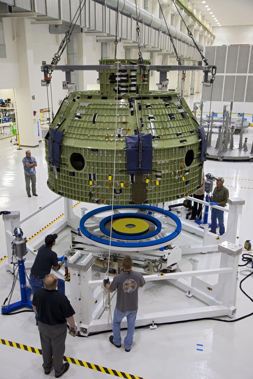 CAPE CANAVERAL, Fla. – Inside the Operations and Checkout Building at NASA’s Kennedy Space Center in Florida, technicians monitor the progress as a crane lowers the Orion Exploration Flight Test 1 crew module toward the base of a birdcage tool. The birdcage will be used to continue installation of external components in preparation for Orion’s first uncrewed test flight in 2014 atop a Delta IV rocket. Orion is the exploration spacecraft designed to carry crews to space beyond low Earth orbit. It will provide emergency abort capability, sustain the crew during the space travel and provide safe re-entry from deep space return velocities. A second uncrewed flight test is scheduled for 2017 on NASA’s Space Launch System rocket. For more information, visit http://www.nasa.gov/orion. Photo credit: NASA/Kim Shiflett