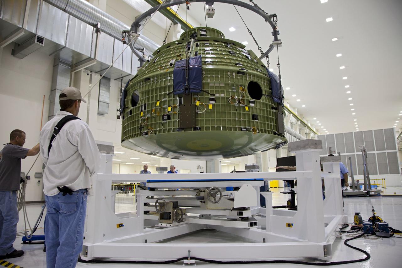 CAPE CANAVERAL, Fla. – Inside the Operations and Checkout Building at NASA’s Kennedy Space Center in Florida, technicians monitor the progress as a crane lowers the Orion Exploration Flight Test 1 crew module toward the base of a birdcage tool. The birdcage will be used to continue installation of external components in preparation for Orion’s first uncrewed test flight in 2014 atop a Delta IV rocket. Orion is the exploration spacecraft designed to carry crews to space beyond low Earth orbit. It will provide emergency abort capability, sustain the crew during the space travel and provide safe re-entry from deep space return velocities. A second uncrewed flight test is scheduled for 2017 on NASA’s Space Launch System rocket. For more information, visit http://www.nasa.gov/orion. Photo credit: NASA/Kim Shiflett