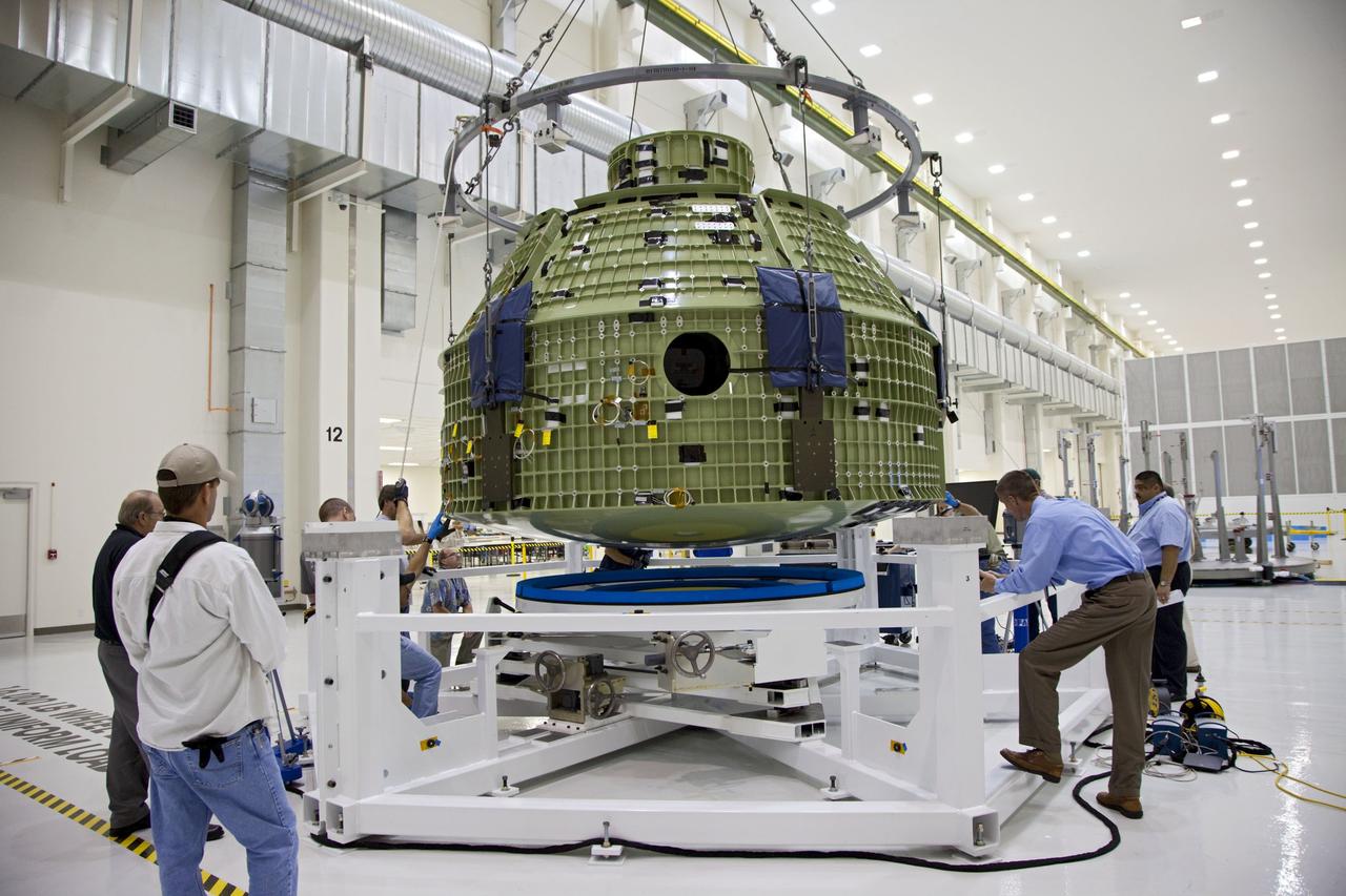 CAPE CANAVERAL, Fla. – Inside the Operations and Checkout Building at NASA’s Kennedy Space Center in Florida, technicians monitor the progress as a crane lowers the Orion Exploration Flight Test 1 crew module toward the base of a birdcage tool. The birdcage will be used to continue installation of external components in preparation for Orion’s first uncrewed test flight in 2014 atop a Delta IV rocket.     Orion is the exploration spacecraft designed to carry crews to space beyond low Earth orbit. It will provide emergency abort capability, sustain the crew during the space travel and provide safe re-entry from deep space return velocities. A second uncrewed flight test is scheduled for 2017 on NASA’s Space Launch System rocket. For more information, visit http://www.nasa.gov/orion. Photo credit: NASA/Kim Shiflett
