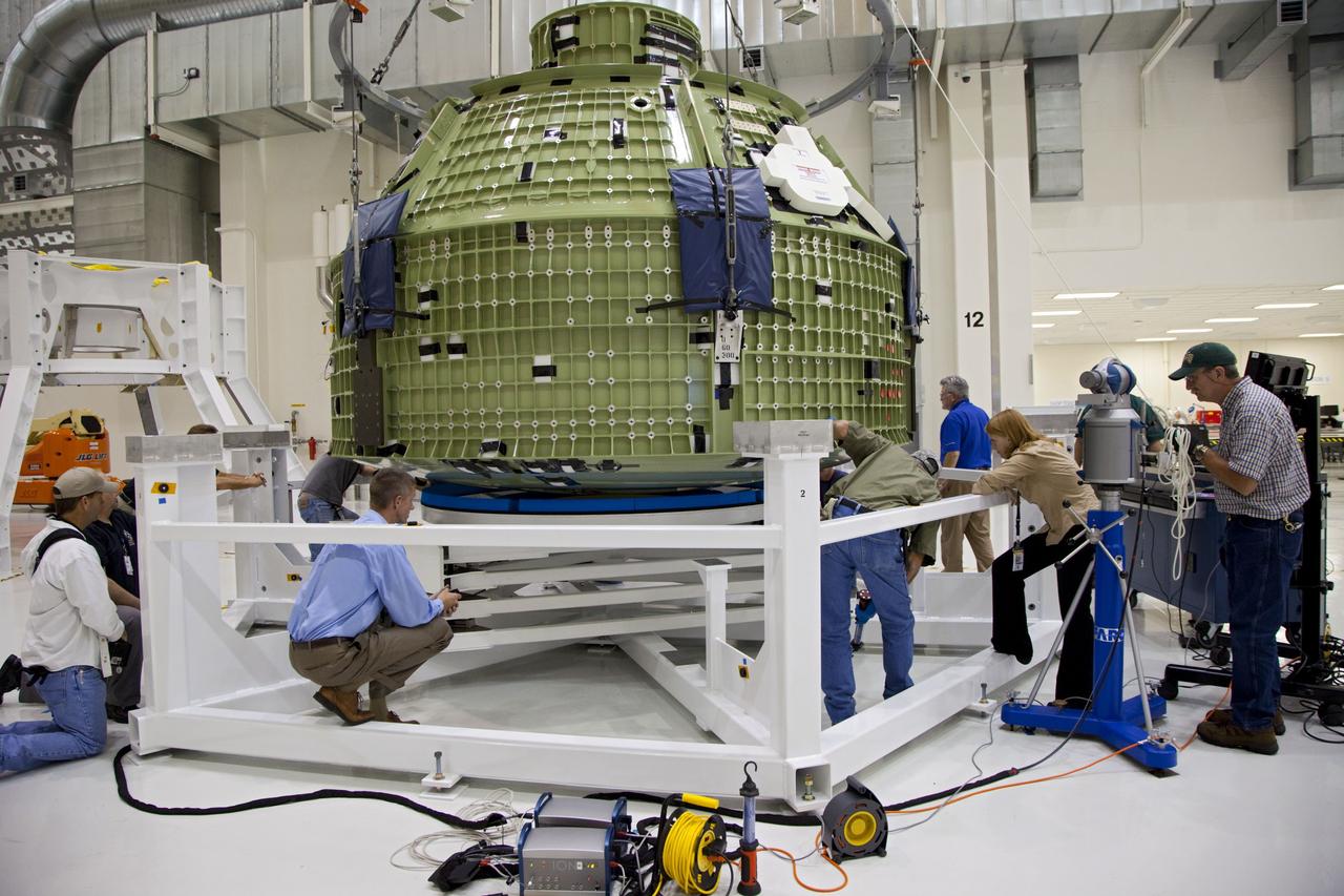 CAPE CANAVERAL, Fla. – Inside the Operations and Checkout Building at NASA’s Kennedy Space Center in Florida, technicians provide assistance as a crane lowers the Orion Exploration Flight Test 1 crew module onto the base of a birdcage tool. The birdcage will be used to continue installation of external components in preparation for Orion’s first uncrewed test flight in 2014 atop a Delta IV rocket. Orion is the exploration spacecraft designed to carry crews to space beyond low Earth orbit. It will provide emergency abort capability, sustain the crew during the space travel and provide safe re-entry from deep space return velocities. A second uncrewed flight test is scheduled for 2017 on NASA’s Space Launch System rocket. For more information, visit http://www.nasa.gov/orion. Photo credit: NASA/Kim Shiflett