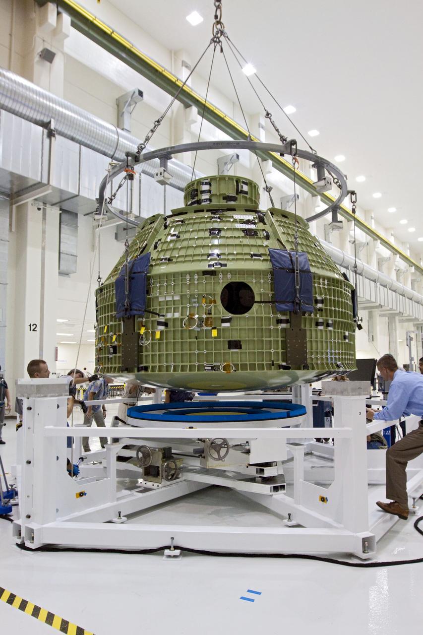 CAPE CANAVERAL, Fla. – Inside the Operations and Checkout Building at NASA’s Kennedy Space Center in Florida, technicians provide assistance as a crane lowers the Orion Exploration Flight Test 1 crew module onto the base of a birdcage tool. The birdcage will be used to continue installation of external components in preparation for Orion’s first uncrewed test flight in 2014 atop a Delta IV rocket. Orion is the exploration spacecraft designed to carry crews to space beyond low Earth orbit. It will provide emergency abort capability, sustain the crew during the space travel and provide safe re-entry from deep space return velocities. A second uncrewed flight test is scheduled for 2017 on NASA’s Space Launch System rocket. For more information, visit http://www.nasa.gov/orion. Photo credit: NASA/Kim Shiflett