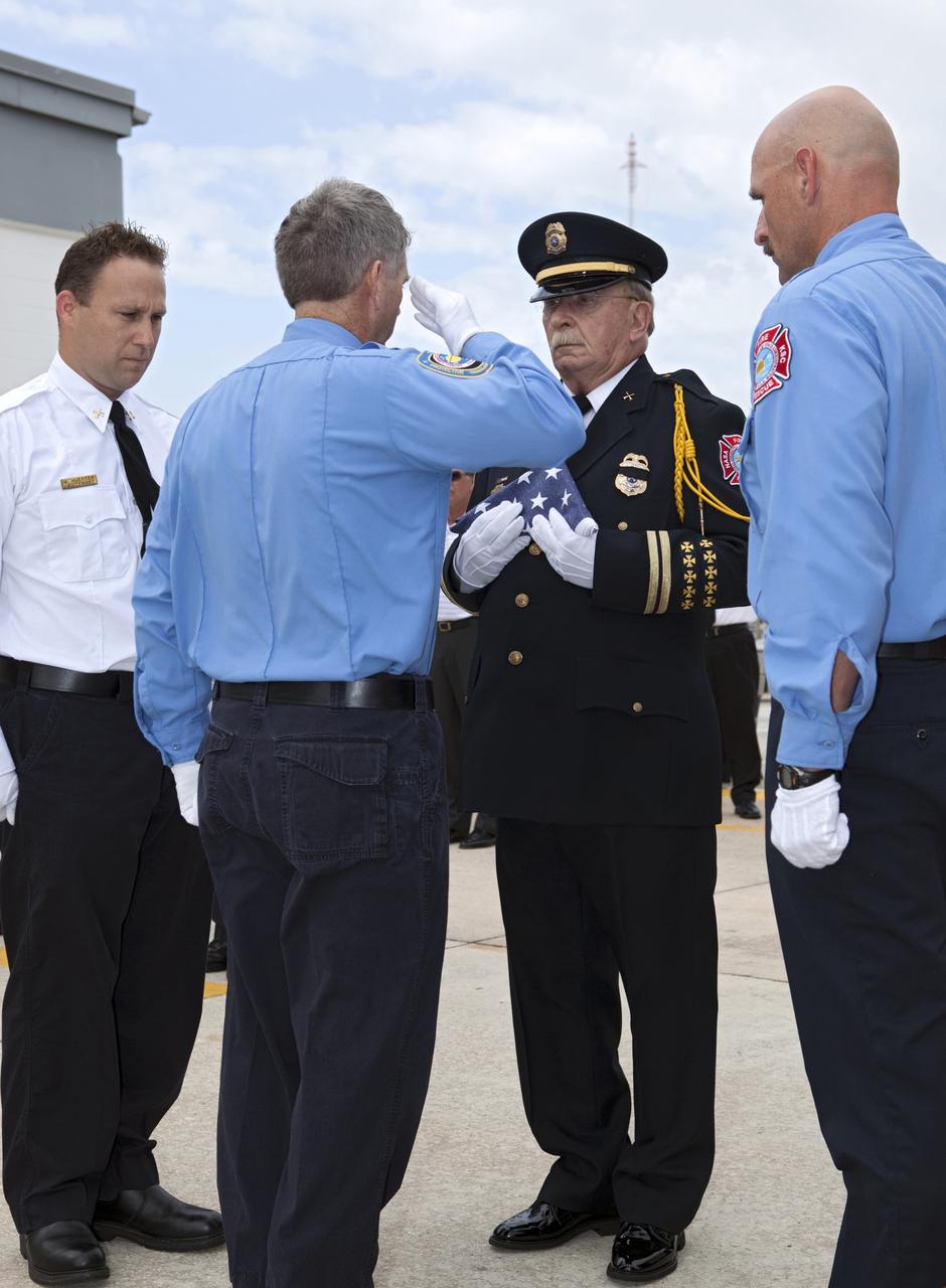 CAPE CANAVERAL, Fla. – At Fire Station 1 at NASA’s Kennedy Space Center in Florida, Fire and Rescue personnel salute or stand at attention during a flag folding ceremony at the 9/11 memorial dedication ceremony.    Kennedy Fire and Rescue Services commemorated the 11th anniversary of 9/11 with a ceremony that included a minute of silence at 10:28 a.m., which was the moment of collapse of the north tower of the World Trade Center. Kennedy center-wide emergency units dispatched by Fire Control engaged in one-minute sirens, the new memorial was dedicated and the Honor Guard performed a flag-folding ceremony. Photo credit: NASA/Dimitri Gerondidakis