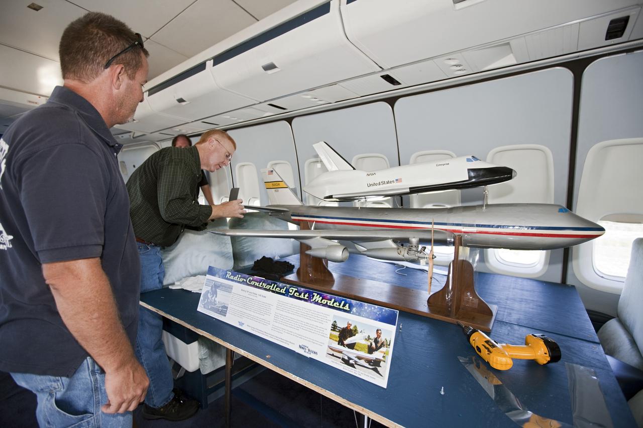 CAPE CANAVERAL, Fla. – Reporters look over a model of the Shuttle Carrier Aircraft, or SCA, and a space shuttle during a tour of the real Shuttle Carrier Aircraft. The model is a radio-controlled scale version of the modified 747 that was used to test theories for how the space shuttle would separate from the SCA during approach and landing tests. Photo credit: NASA/Kim Shiflett