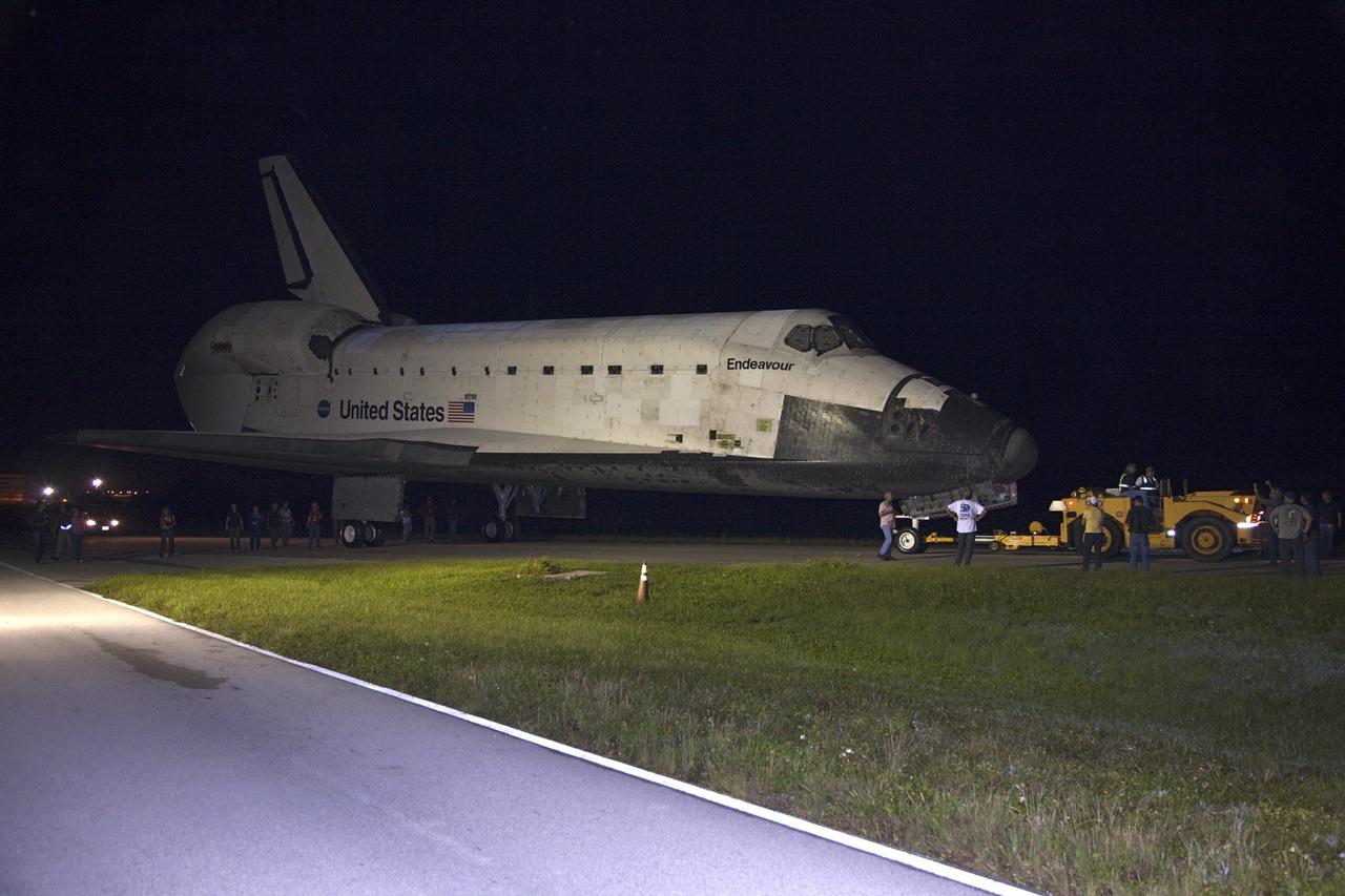 CAPE CANAVERAL, Fla. – Workers escort space shuttle Endeavour as it is towed to the Mate-Demate Device, or MDD, at NASA's Kennedy Space Center in Florida after being backed out of the Vehicle Assembly Building. The MDD is located at the Shuttle Landing Facility at Kennedy. The shuttle will be lifted and connected to the top of NASA's Shuttle Carrier Aircraft SCA, a modified 747 jetliner. The shuttle has been fitted with an aerodynamic tailcone for its flight aboard the SCA to Los Angeles where it will be placed on public display. Photo credit: NASA/ Frankie Martin