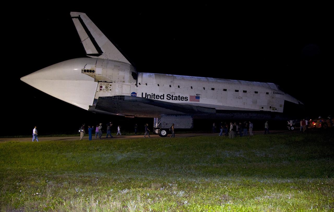 CAPE CANAVERAL, Fla. – Workers escort space shuttle Endeavour as it is towed to the Mate-Demate Device, or MDD, at NASA's Kennedy Space Center in Florida after being backed out of the Vehicle Assembly Building. The MDD is located at the Shuttle Landing Facility at Kennedy. The shuttle will be lifted and connected to the top of NASA's Shuttle Carrier Aircraft SCA, a modified 747 jetliner. The shuttle has been fitted with an aerodynamic tailcone for its flight aboard the SCA to Los Angeles where it will be placed on public display. Photo credit: NASA/ Frankie Martin