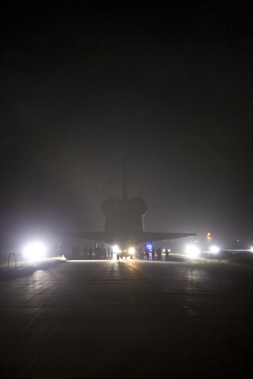 CAPE CANAVERAL, Fla. - Workers escort space shuttle Endeavour as it is towed to the Mate-Demate Device, or MDD, at NASA's Kennedy Space Center in Florida after being backed out of the Vehicle Assembly Building. The MDD is located at the Shuttle Landing Facility at Kennedy. The shuttle will be lifted and connected to the top of NASA's Shuttle Carrier Aircraft SCA, a modified 747 jetliner. The shuttle has been fitted with an aerodynamic tailcone for its flight aboard the SCA to Los Angeles where it will be placed on public display. Photo credit: NASA/Dmitri Gerondidakis