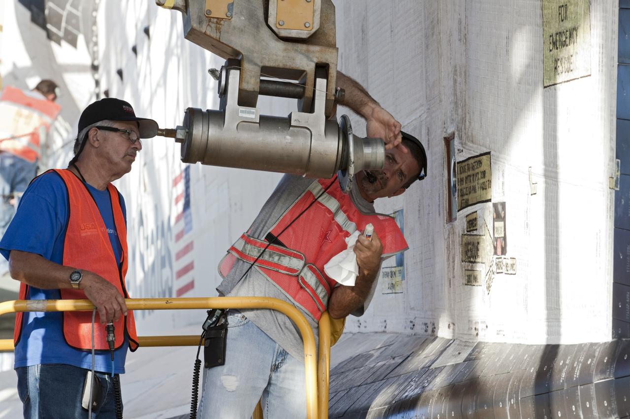 CAPE CANAVERAL, Fla. – Workers inspect an attachment point before it is connected to space shuttle Endeavour so the shuttle can be raised for connection to the Shuttle Carrier Aircraft, or SCA. The shuttle is inside the Mate-Demate Device, or MDD, at the Shuttle Landing Facility at NASA's Kennedy Space Center in Florida. The SCA will carry Endeavour to Los Angeles where it will be placed on public display. Photo credit: NASA/Kim Shiflett