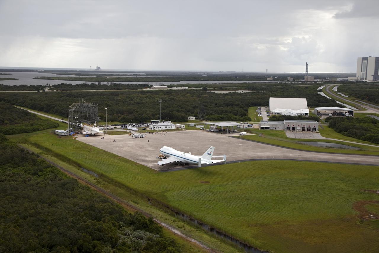 CAPE CANAVERAL, Fla. – Space shuttle Endeavour is seen inside the Mate-Demate Device, or MDD, at the Shuttle Landing Facility at NASA's Kennedy Space Center in Florida. The Shuttle Carrier Aircraft, or SCA, is seen on the ramp. The SCA will carry Endeavour to Los Angeles where it will be placed on public display. The center's Vehicle Assembly Building, or VAB, and the mobile launcher built for the Space Launch System are also visible in the background. The SCA will carry Endeavour to Los Angeles where it will be placed on public display. Photo credit: NASA/Kim Shiflett