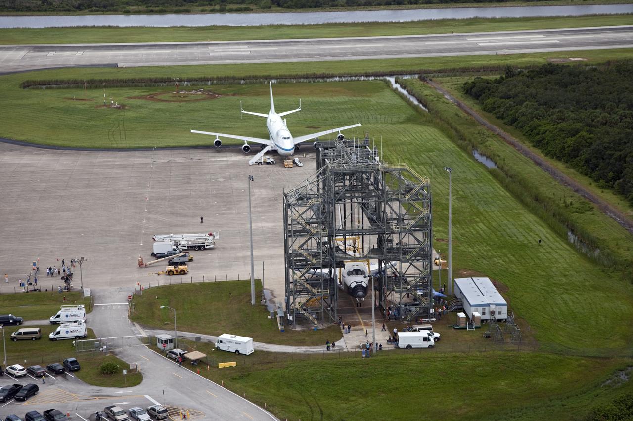 CAPE CANAVERAL, Fla. – Space shuttle Endeavour is seen inside the Mate-Demate Device, or MDD, at the Shuttle Landing Facility at NASA's Kennedy Space Center in Florida. The Shuttle Carrier Aircraft, or SCA, is seen on the ramp. The SCA will carry Endeavour to Los Angeles where it will be placed on public display. The center's Vehicle Assembly Building, or VAB, and the mobile launcher built for the Space Launch System are also visible in the background. Photo credit: NASA/Kim Shiflett