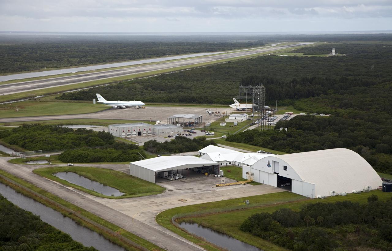 CAPE CANAVERAL, Fla. – Space shuttle Endeavour is seen inside the Mate-Demate Device, or MDD, at the Shuttle Landing Facility, or SLF, at NASA's Kennedy Space Center in Florida. The Shuttle Carrier Aircraft, or SCA, is seen on the ramp. The SCA will carry Endeavour to Los Angeles where it will be placed on public display. The center's Reusable Launch Vehicle hangar and other structures at the SLF are also visible. Photo credit: NASA/Kim Shiflett