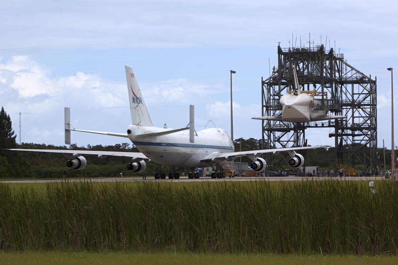 CAPE CANAVERAL, Fla. – NASA's Shuttle Carrier Aircraft, or SCA, rolls toward space shuttle Endeavour, suspended in the mate-demate device at the Shuttle Landing Facility at NASA's Kennedy Space Center in Florida. The shuttle will be lowered and connected to the top of the SCA with the aid of the device. The shuttle has been fitted with an aerodynamic tailcone for its upcoming ferry flight. The SCA, a modified 747 jetliner, will fly Endeavour to Los Angeles where it will be placed on public display at the California Science Center. This is the final ferry flight scheduled in the Space Shuttle Program era. For more information on the shuttles' transition and retirement, visit http://www.nasa.gov/transition. Photo credit: NASA/Dimitri Gerondidakis