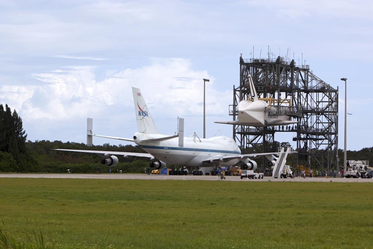 CAPE CANAVERAL, Fla. – NASA's Shuttle Carrier Aircraft, or SCA, rolls toward space shuttle Endeavour, suspended in the mate-demate device at the Shuttle Landing Facility at NASA's Kennedy Space Center in Florida. The shuttle will be lowered and connected to the top of the SCA with the aid of the device. The shuttle has been fitted with an aerodynamic tailcone for its upcoming ferry flight. The SCA, a modified 747 jetliner, will fly Endeavour to Los Angeles where it will be placed on public display at the California Science Center. This is the final ferry flight scheduled in the Space Shuttle Program era. For more information on the shuttles' transition and retirement, visit http://www.nasa.gov/transition. Photo credit: NASA/Dimitri Gerondidakis