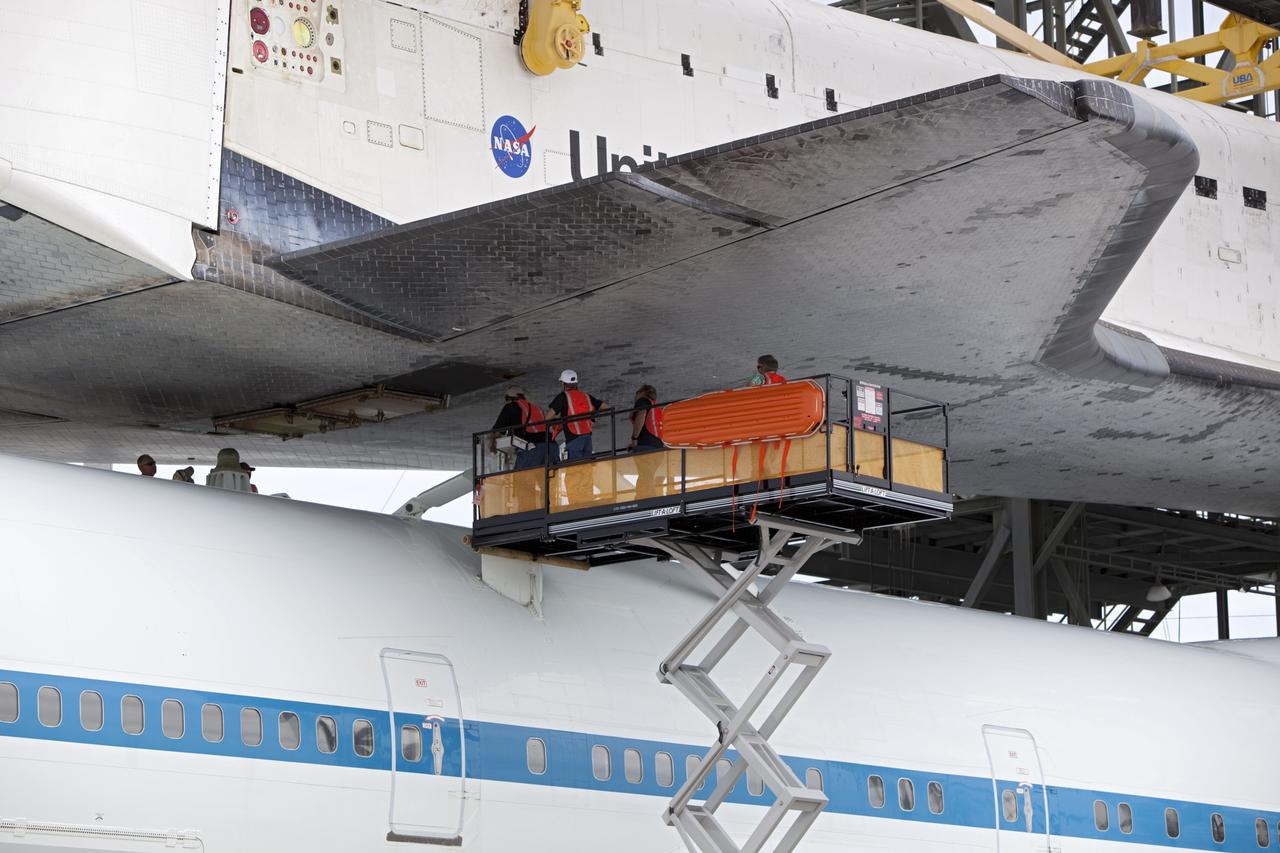 CAPE CANAVERAL, Fla. – United Space Alliance technicians watch as space shuttle Endeavour is lowered onto the Shuttle Carrier Aircraft, or SCA, at the Shuttle Landing Facility at NASA's Kennedy Space Center in Florida. The SCA, a modified 747 jetliner, will fly Endeavour to Los Angeles where it will be placed on public display. Photo credit: NASA/ Dmitri Gerondidakis
