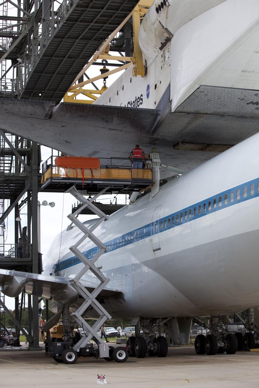 CAPE CANAVERAL, Fla. – United Space Alliance technicians watch as space shuttle Endeavour is lowered onto the Shuttle Carrier Aircraft, or SCA, at the Shuttle Landing Facility at NASA's Kennedy Space Center in Florida. The SCA, a modified 747 jetliner, will fly Endeavour to Los Angeles where it will be placed on public display. Photo credit: NASA/ Dimitri Gerondidakis