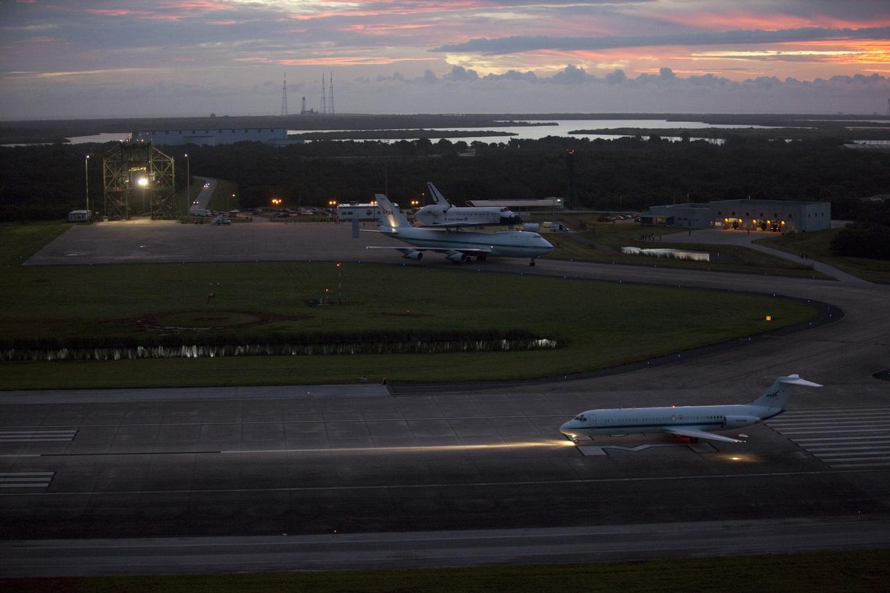 CAPE CANAVERAL, Fla. – At the Shuttle Landing Facility at NASA's Kennedy Space Center in Florida, a pathfinder aircraft, in the foreground, prepares to take off. The pathfinder will fly ahead of NASA's Shuttle Carrier Aircraft, or SCA, with the space shuttle Endeavour mounted atop, also preparing to taxi away from the mate-demate device for its ferry flight to California.    The SCA, a modified 747 jetliner, will fly Endeavour to Los Angeles where it will be placed on public display at the California Science Center. This is the final ferry flight scheduled in the Space Shuttle Program era. For more information on the shuttles' transition and retirement, visit http://www.nasa.gov/transition.  Photo credit: NASA/Kim Shiflett