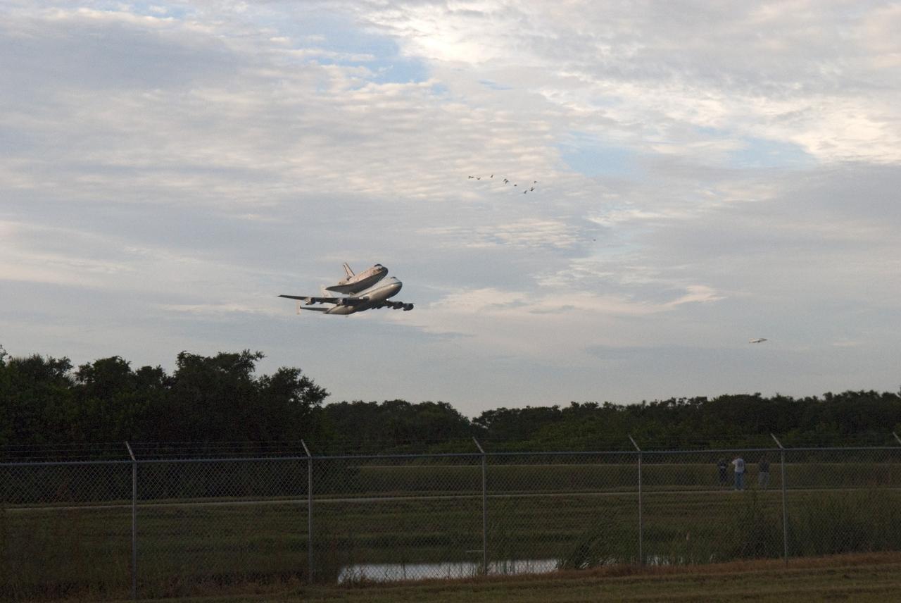 CAPE CANAVERAL, Fla. – At the Shuttle Landing Facility at NASA's Kennedy Space Center in Florida, NASA's Shuttle Carrier Aircraft, or SCA, with the space shuttle Endeavour mounted atop, is escorted by a T-38 jet and a flock of birds as it makes a low-level pass after taking off for its ferry flight to California.    The SCA, a modified 747 jetliner, will fly Endeavour to Los Angeles where it will be placed on public display at the California Science Center. This is the final ferry flight scheduled in the Space Shuttle Program era. For more information on the shuttles' transition and retirement, visit http://www.nasa.gov/transition.  Photo credit: NASA/George Sampson