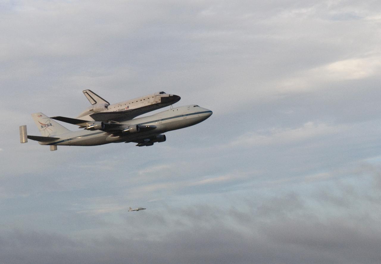 CAPE CANAVERAL, Fla. – At the Shuttle Landing Facility at NASA's Kennedy Space Center in Florida, NASA's Shuttle Carrier Aircraft, or SCA, with the space shuttle Endeavour mounted atop, is escorted by a T-38 jet as it makes a low-level pass after taking off for its ferry flight to California.    The SCA, a modified 747 jetliner, will fly Endeavour to Los Angeles where it will be placed on public display at the California Science Center. This is the final ferry flight scheduled in the Space Shuttle Program era. For more information on the shuttles' transition and retirement, visit http://www.nasa.gov/transition.  Photo credit: NASA/George Sampson