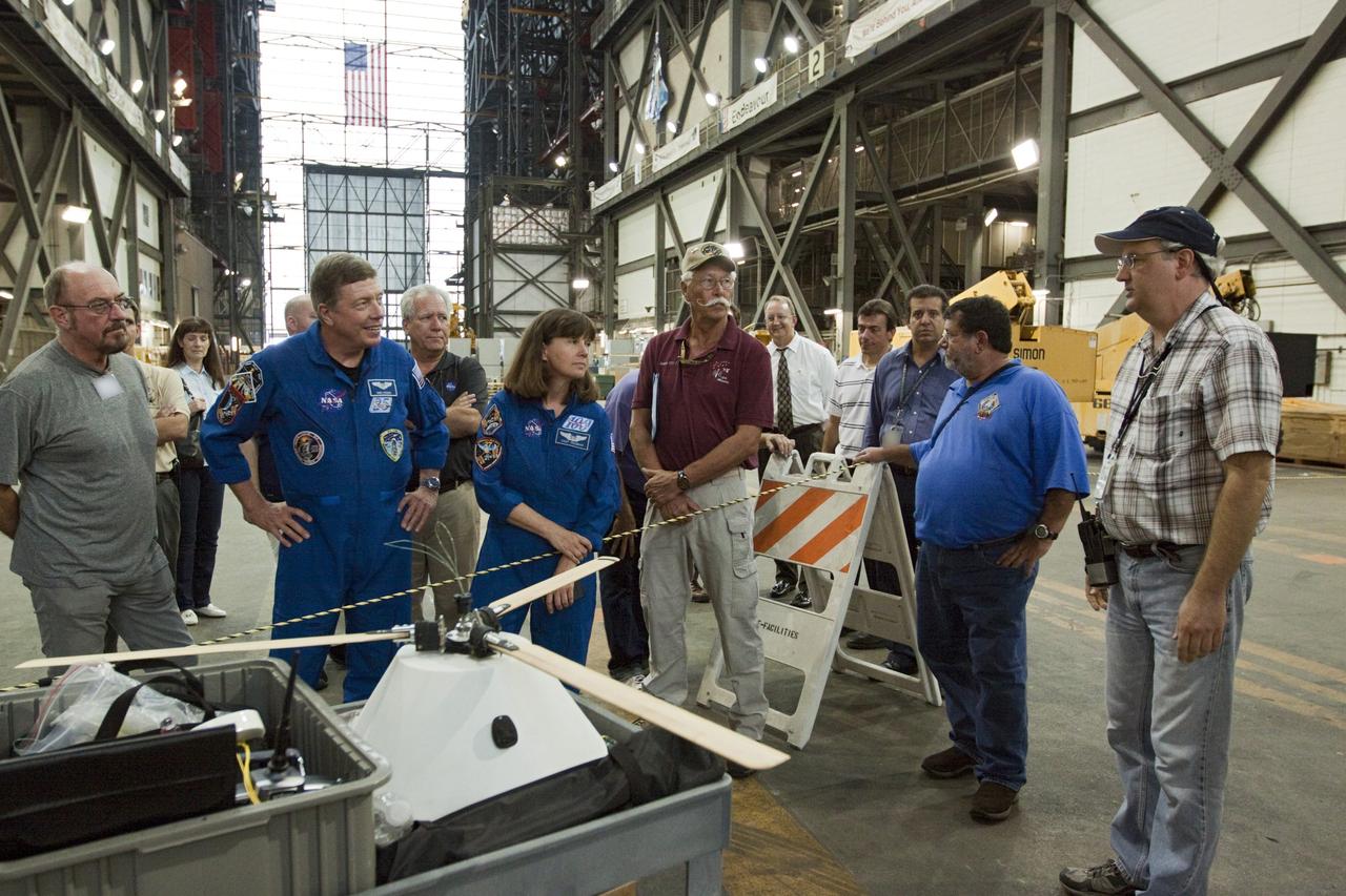 CAPE CANAVERAL, Fla. - Astronauts Mike Fossum and Cady Coleman, both in blue flight suits, look over the model capsule fit with rotor blades ahead of tests inside the Vehicle Assembly Building at NASA's Kennedy Space Center in Florida. NASA's Johnson Space Center Aerospace Engineer Jeff Hagen, right, fields questions about the project. The design would give a capsule the stability and control of a helicopter, but would not be powered. Instead, the wind passing over the rotors as the capsule descends would make the blades turn, a process called auto-rotation. The intent is to give real spacecraft a soft landing with enough control that they could touch down anywhere in the world, whether it be a runway or parking lot. In other words, wherever a helicopter could land, a spacecraft could land, too. Photo credit: NASA/Kim Shiflett