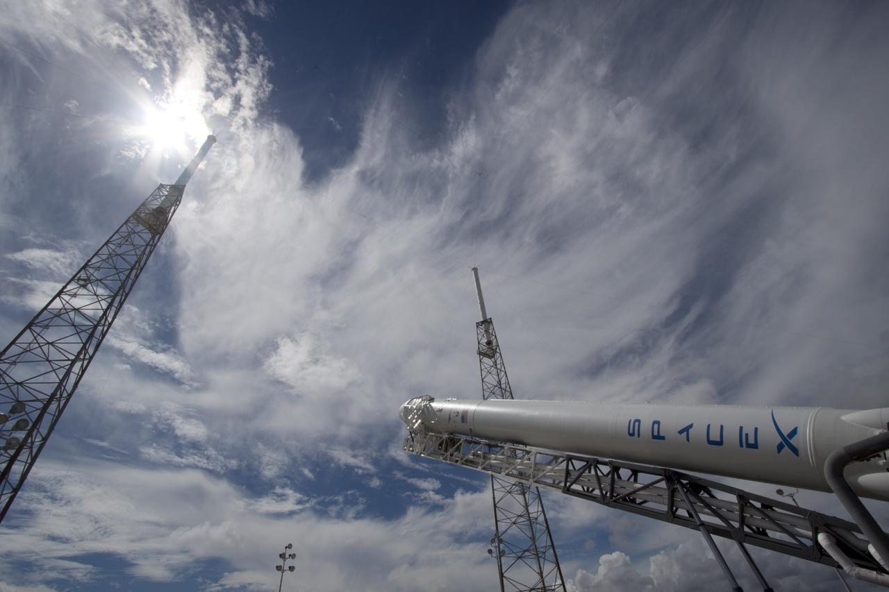 CAPE CANAVERAL, Fla. -- A Falcon 9 rocket with a Dragon capsule secured atop begins to rise into a vertical position between the lightning masts on the pad at Space Launch Complex 40 on Cape Canaveral Air Force Station in Florida.     Space Exploration Technologies Corp., or SpaceX, built both the rocket and capsule for NASA's first Commercial Resupply Services, or CRS-1, mission to the International Space Station.  The vertical lift was complete at 1 p.m. EDT.  SpaceX CRS-1 is an important step toward making America’s microgravity research program self-sufficient by providing a way to deliver and return significant amounts of cargo, including science experiments, to and from the orbiting laboratory. Launch is scheduled for 8:35 p.m. EDT on Oct. 7. NASA has contracted for 12 commercial resupply flights from SpaceX and eight from the Orbital Sciences Corp. For more information, visit http://www.nasa.gov/mission_pages/station/living/launch/index.html.  Photo credit: NASA/Jim Grossmann