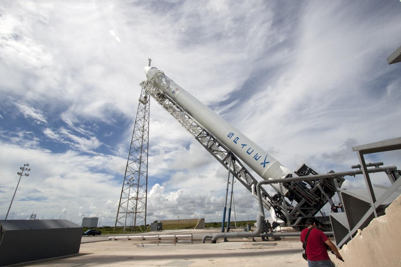 CAPE CANAVERAL, Fla. -- A Falcon 9 rocket with a Dragon capsule secured atop rises into a vertical position between the lightning masts on the pad at Space Launch Complex 40 on Cape Canaveral Air Force Station in Florida.     Space Exploration Technologies Corp., or SpaceX, built both the rocket and capsule for NASA's first Commercial Resupply Services, or CRS-1, mission to the International Space Station.  The vertical lift was complete at 1 p.m. EDT.  SpaceX CRS-1 is an important step toward making America’s microgravity research program self-sufficient by providing a way to deliver and return significant amounts of cargo, including science experiments, to and from the orbiting laboratory. Launch is scheduled for 8:35 p.m. EDT on Oct. 7. NASA has contracted for 12 commercial resupply flights from SpaceX and eight from the Orbital Sciences Corp. For more information, visit http://www.nasa.gov/mission_pages/station/living/launch/index.html.  Photo credit: NASA/Jim Grossmann
