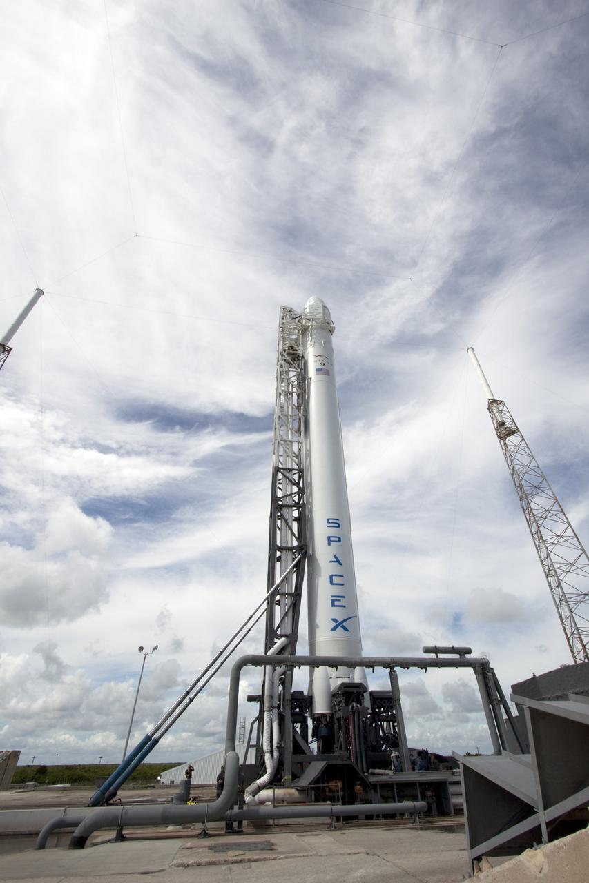 CAPE CANAVERAL, Fla. -- A Falcon 9 rocket with a Dragon capsule secured atop stands upright between the lightning masts on the pad at Space Launch Complex 40 on Cape Canaveral Air Force Station in Florida.    Space Exploration Technologies Corp., or SpaceX, built both the rocket and capsule for NASA's first Commercial Resupply Services, or CRS-1, mission to the International Space Station.  The vertical lift was complete at 1 p.m. EDT.  SpaceX CRS-1 is an important step toward making America’s microgravity research program self-sufficient by providing a way to deliver and return significant amounts of cargo, including science experiments, to and from the orbiting laboratory. Launch is scheduled for 8:35 p.m. EDT on Oct. 7. NASA has contracted for 12 commercial resupply flights from SpaceX and eight from the Orbital Sciences Corp. For more information, visit http://www.nasa.gov/mission_pages/station/living/launch/index.html.  Photo credit: NASA/Jim Grossmann