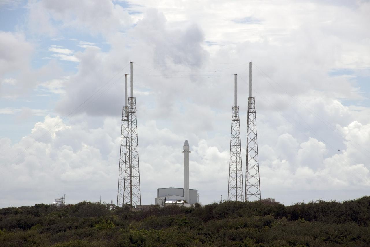 CAPE CANAVERAL, Fla. -- A Falcon 9 rocket with a Dragon capsule secured atop stands upright between the lightning masts on the pad at Space Launch Complex 40 on Cape Canaveral Air Force Station in Florida. Preparations are under way to fuel the rocket for launch.    Space Exploration Technologies Corp., or SpaceX, built both the rocket and capsule for NASA's first Commercial Resupply Services, or CRS-1, mission to the International Space Station.  The vertical lift was complete at 1 p.m. EDT.  SpaceX CRS-1 is an important step toward making America’s microgravity research program self-sufficient by providing a way to deliver and return significant amounts of cargo, including science experiments, to and from the orbiting laboratory. Launch is scheduled for 8:35 p.m. EDT on Oct. 7. NASA has contracted for 12 commercial resupply flights from SpaceX and eight from the Orbital Sciences Corp. For more information, visit http://www.nasa.gov/mission_pages/station/living/launch/index.html.  Photo credit: NASA/Jim Grossmann
