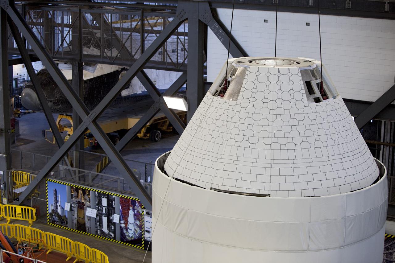 CAPE CANAVERAL, Fla. – An Orion mockup spacecraft atop its service module simulator is lifted in the transfer aisle of the Vehicle Assembly Building, or VAB, at NASA's Kennedy Space Center in Florida. The Orion mockup is exact in details on the outside, but mostly empty on the inside. The work in the VAB is crucial to making sure the designs are accurate. Visible in the background on the left is the space shuttle Atlantis being readied for its move to the Kennedy Space Center Visitor Complex. Orion is the exploration spacecraft designed to carry crews to space beyond low Earth orbit. It will provide emergency abort capability, sustain the crew during the space travel and provide safe re-entry from deep space return velocities. The first unpiloted test flight of the Orion is scheduled to launch in 2014 atop a Delta IV rocket and in 2017 on a Space Launch System rocket. For more information, visit http://www.nasa.gov/orion Photo credit: NASA/ Dmitri Gerondidakis