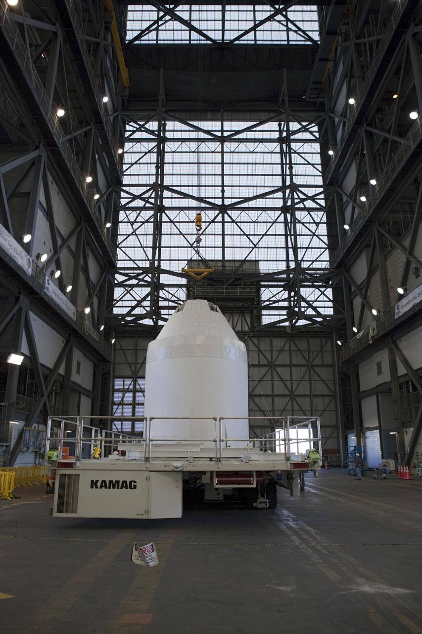 CAPE CANAVERAL, Fla. – An Orion mockup spacecraft atop its service module simulator is lowered onto a transporter in the transfer aisle of the Vehicle Assembly Building, or VAB, at NASA's Kennedy Space Center in Florida. The Orion mockup is exact in details on the outside, but mostly empty on the inside. The work in the VAB is crucial to making sure the designs are accurate. Orion is the exploration spacecraft designed to carry crews to space beyond low Earth orbit. It will provide emergency abort capability, sustain the crew during the space travel and provide safe re-entry from deep space return velocities. The first unpiloted test flight of the Orion is scheduled to launch in 2014 atop a Delta IV rocket and in 2017 on a Space Launch System rocket. For more information, visit http://www.nasa.gov/orion Photo credit: NASA/ Dmitri Gerondidakis