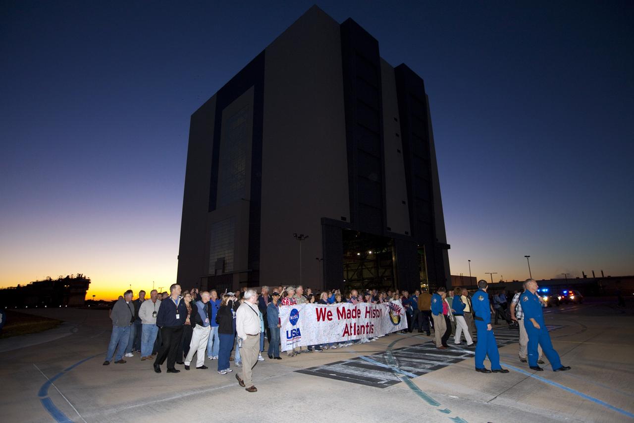 CAPE CANAVERAL, Fla. – STS-135 crew members Sandy Magnus, Rex Walheim, Doug Hurley and Chris Ferguson join space shuttle workers carrying a "We Made History Atlantis" banner as they follow the spacecraft as it is transported on a 10-mile journey to the Kennedy Visitor Complex where it will be put on public display. As part of transition and retirement of the Space Shuttle Program, Atlantis is to be displayed at Kennedy's Visitor Complex beginning in the summer of 2013. Over the course of its 26-year career, Atlantis traveled 125,935,769 miles during 307 days in space over 33 missions. For more information, visit http://www.nasa.gov/transition Photo credit: NASA/ Kim Shiflett