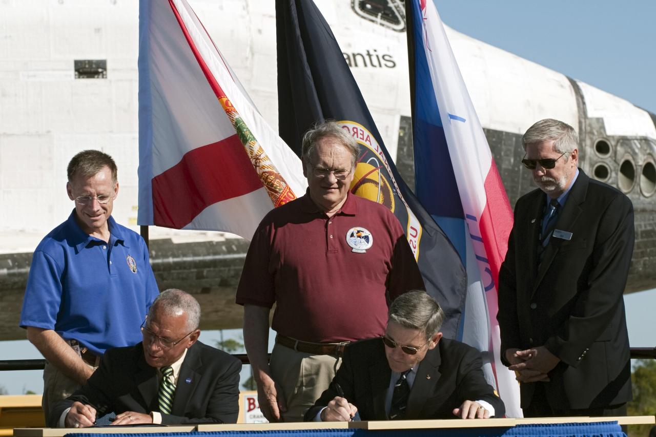 CAPE CANAVERAL, Fla. – At NASA's Kennedy Space Center in Florida, the space shuttle Atlantis pauses during its 10-mile journey to the Kennedy Visitor Complex for a ceremony to commemorate its transfer. NASA Administrator Charles Bolden, seated left, and Kennedy Director Bob Cabana sign documents transferring title of Atlantis from the agency to Kennedy Space Center. Also participating in the ceremony, standing, from left, are Chris Ferguson, who commanded Atlantis's final mission, Karol Bobko, commander of Atlantis' first mission, and Delaware North Companies Parks and Resorts Chief Operating Officer Bill Moore.      As part of transition and retirement of the Space Shuttle Program, Atlantis is to be displayed at Kennedy's visitor complex beginning in the summer of 2013. Over the course of its 26-year career, Atlantis traveled 125,935,769 miles during 307 days in space over 33 missions. For more information, visit http://www.nasa.gov/transition Photo credit: NASA/ Tony Gray