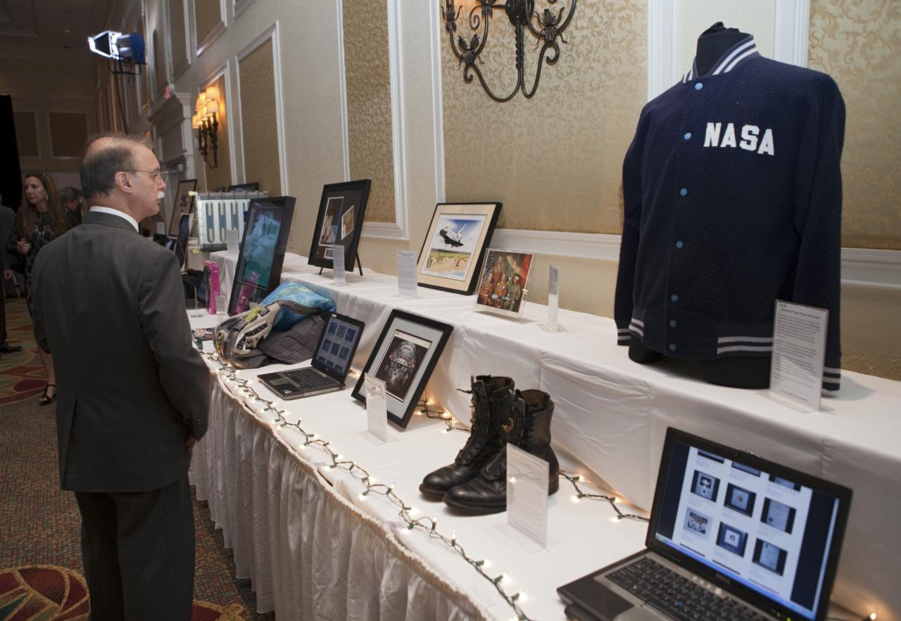 CAPE CANAVERAL, Fla. – A guest checks out an item available for auction at the Astronaut Scholarship Foundation's dinner at the Radisson Resort at the Port in Cape Canaveral celebrating the 40th anniversary of Apollo 17. The auction of space-related memorabilia was held with proceeds supporting college scholarships for students who exhibit imagination and exceptional performance in science, technology, engineering and math.  The gala commemorating the anniversary of Apollo 17 included mission commander Eugene Cernan and other astronauts who flew Apollo missions. Launched Dec. 7, 1972, Cernan and lunar module pilot Harrison Schmitt landed in the moon's Taurus-Littrow highlands while command module pilot Ronald Evans remained in lunar orbit operating a scientific instrument module. For more information, visit http://www-pao.ksc.nasa.gov/history/apollo/apollo-17/apollo-17.htm Photo credit: NASA/Kim Shiflett
