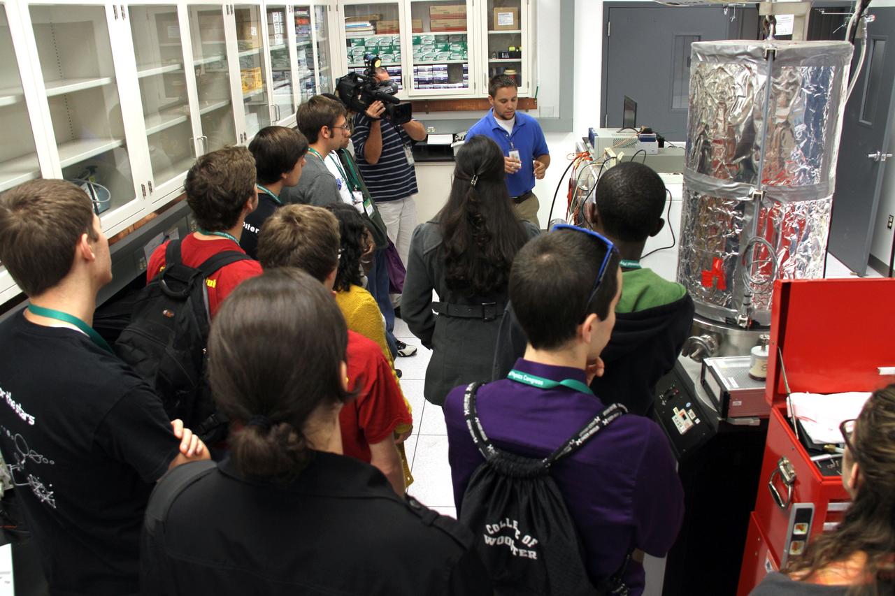 CAPE CANAVERAL, Fla. -- – Inside a laboratory in the Engineering Development Laboratory, or EDL, at NASA’s Kennedy Space Center in Florida, research scientist Michael Johansen, in the blue polo shirt, describes dust mitigation technology to a group of Society of Physics students.    About 800 graduate and undergraduate physics students toured Kennedy facilities. A group of about 40 students toured laboratories in the Operations and Checkout Building and the EDL during their visit. The physics students were in Orlando for the 2012 Quadrennial Physics Congress. Photo credit: NASA/Cory Huston