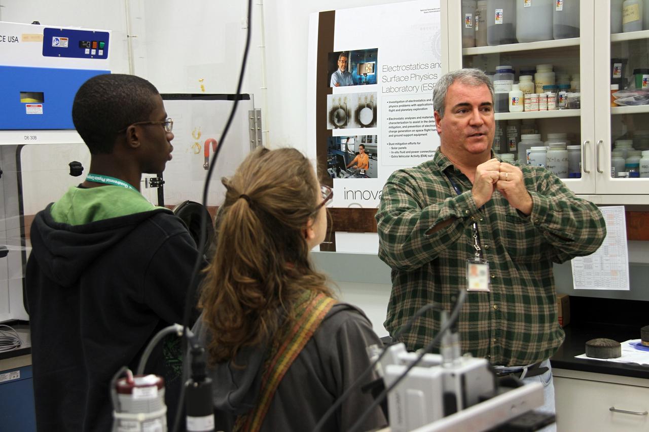 CAPE CANAVERAL, Fla. -- Inside a laboratory in the Engineering Development Laboratory, or EDL, at NASA’s Kennedy Space Center in Florida, research scientist Michael Hogue, in the green plaid shirt, describes several technologies to a group of Society of Physics students.    About 800 graduate and undergraduate physics students toured Kennedy facilities. A group of about 40 students toured laboratories in the Operations and Checkout Building and the EDL during their visit. The physics students were in Orlando for the 2012 Quadrennial Physics Congress. Photo credit: NASA/Cory Huston