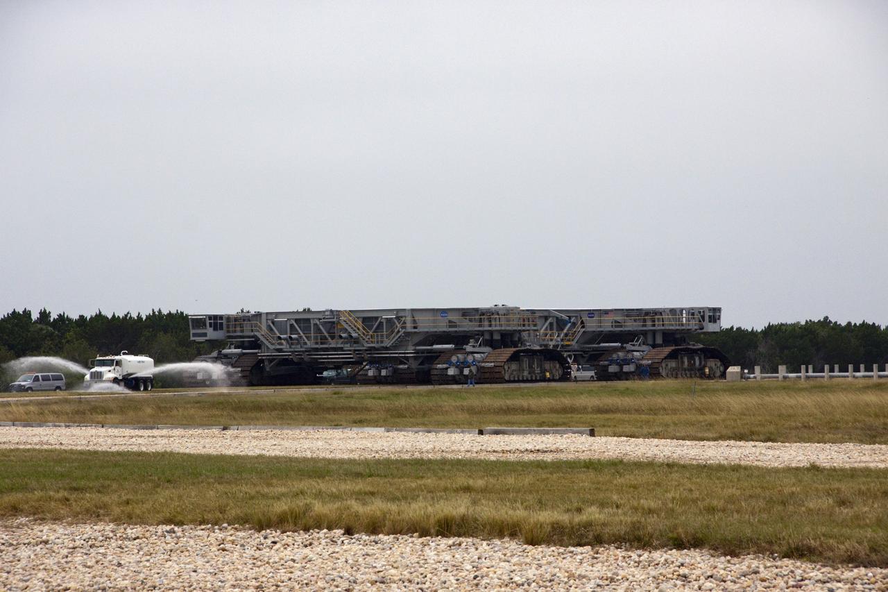 CAPE CANAVERAL, Fla. -- A truck sprays water on the gravel crawler way at NASA's Kennedy Space Center in Florida as crawler-transporter No. 2 is undergoing testing at Launch Pad 39A. The activity is designed to check out recently completed modifications to ensure the crawler-transporter's ability to carry launch vehicles such as the space agency's Space Launch System heavy-lift rocket to the pad. NASA's Ground Systems Development and Operations Program is leading the 20-year life-extension project for the crawler. A pair of behemoth machines called crawler-transporters has carried the load of taking rockets and spacecraft to the launch pad for more than 40 years at NASA’s Kennedy Space Center in Florida. Each weighing six and a half million pounds and larger in size than a professional baseball infield, the crawler-transporters are powered by locomotive and large electrical power generator engines. The crawler-transporters will stand ready to keep up the work for the next generation of launch vehicles to lift astronauts into space. For more information, visit http://www.nasa.gov/exploration/systems/ground/index.html Photo credit: NASA/ Jim Grossmann