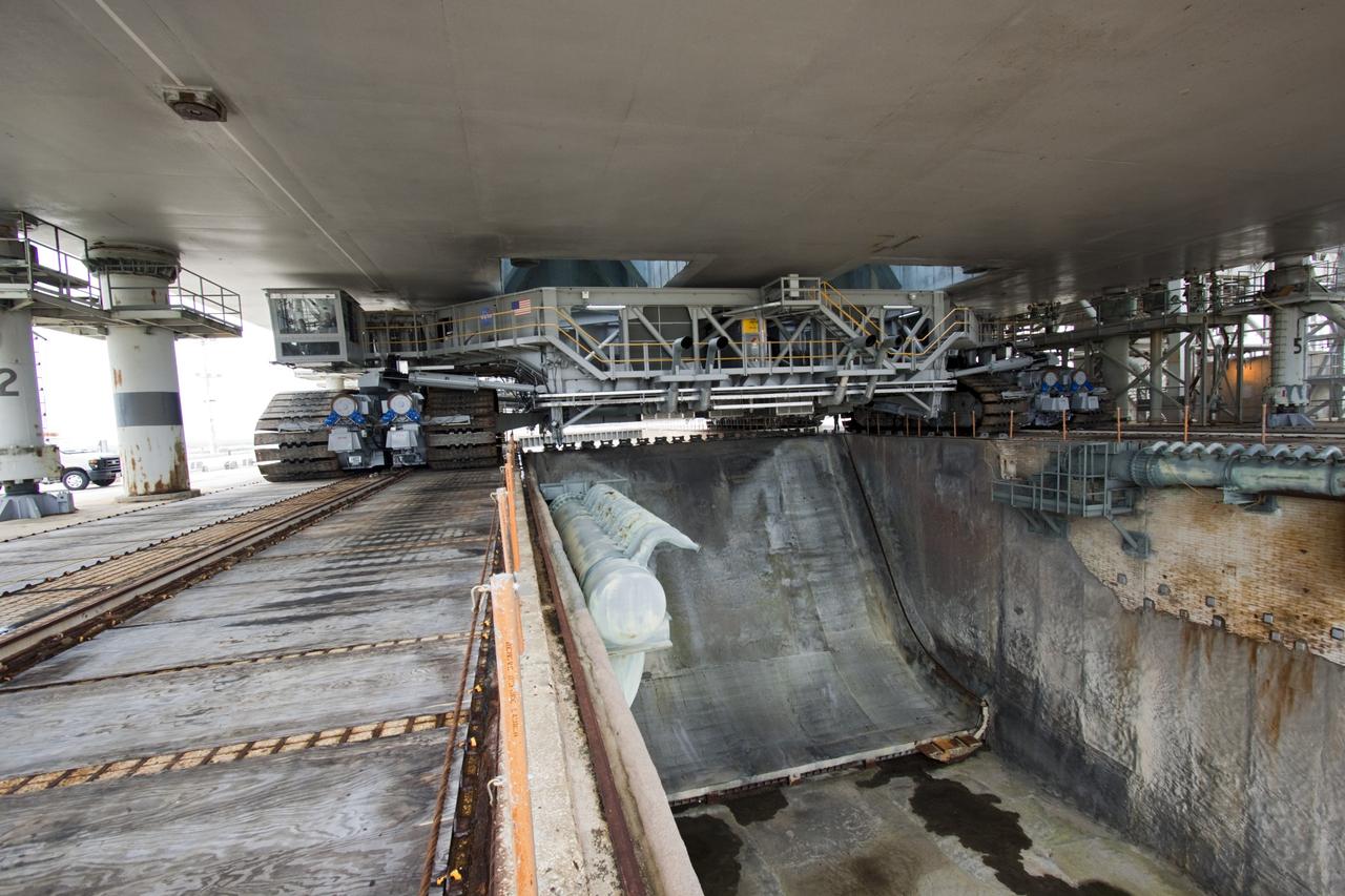 CAPE CANAVERAL, Fla. -- Viewed from under a space shuttle era mobile launcher platform on Launch Pad 39A at NASA's Kennedy Space Center in Florida, crawler-transporter No. 2 moves under. The activity was part of testing to check out recently completed modifications to ensure its ability to carry launch vehicles such as the space agency's Space Launch System heavy-lift rocket to the pad. NASA's Ground Systems Development and Operations Program is leading the 20-year life-extension project for the crawler. A pair of behemoth machines called crawler-transporters has carried the load of taking rockets and spacecraft to the launch pad for more than 40 years at NASA’s Kennedy Space Center in Florida. Each weighing six and a half million pounds and larger in size than a professional baseball infield, the crawler-transporters are powered by locomotive and large electrical power generator engines. The crawler-transporters will stand ready to keep up the work for the next generation of launch vehicles to lift astronauts into space. For more information, visit http://www.nasa.gov/exploration/systems/ground/index.html Photo credit: NASA/ Jim Grossmann