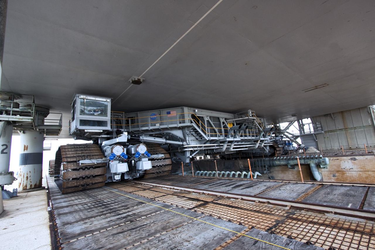 CAPE CANAVERAL, Fla. -- Viewed from under a space shuttle era mobile launcher platform on Launch Pad 39A at NASA's Kennedy Space Center in Florida, crawler-transporter No. 2 moves under. The activity was part of testing to check out recently completed modifications to ensure its ability to carry launch vehicles such as the space agency's Space Launch System heavy-lift rocket to the pad. NASA's Ground Systems Development and Operations Program is leading the 20-year life-extension project for the crawler. A pair of behemoth machines called crawler-transporters has carried the load of taking rockets and spacecraft to the launch pad for more than 40 years at NASA’s Kennedy Space Center in Florida. Each weighing six and a half million pounds and larger in size than a professional baseball infield, the crawler-transporters are powered by locomotive and large electrical power generator engines. The crawler-transporters will stand ready to keep up the work for the next generation of launch vehicles to lift astronauts into space. For more information, visit http://www.nasa.gov/exploration/systems/ground/index.html Photo credit: NASA/ Jim Grossmann
