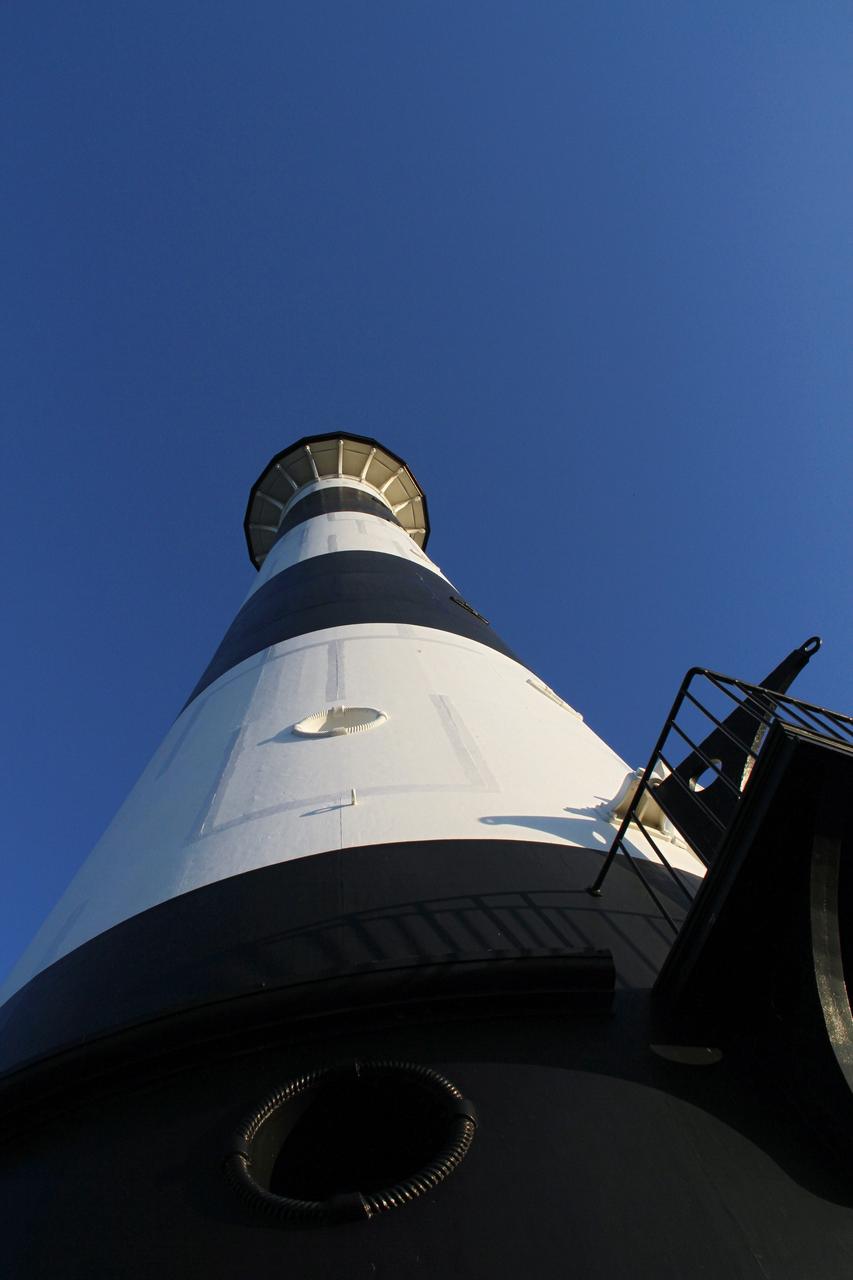 CAPE CANAVERAL AIR FORCE STATION, Fla. – This view looking up contrasts the black and white lighthouse at Cape Canaveral Air Force Station against the Florida sky. The Canaveral light is the only one owned by the U.S. Air Force. In 2000, the Coast Guard transferred ownership of the lighthouse structure and its grounds to the Air Force, which is now responsible for maintaining it. The U.S. Coast Guard continues to operate the beacon as an active navigational aid. The first lighthouse at Cape Canaveral was built near the tip of the Cape in 1848. The structure was only about 60 feet high with a rather dim light powered by whale oil. In 1859, work began nearby on a new, taller iron structure. Construction was halted during the Civil War, and the lighthouse finally was finished in 1868. The structure, with a brick lining inside its iron exterior, was painted with its "daymark" black and white horizontal bands in 1873 to make it easier to identify during the day as a navigation point. Between 1892 and 1894, the lighthouse was dismantled and moved to its new home about a mile from the coast, where it stands today. Photo credit: NASA/Ben Smegelsky