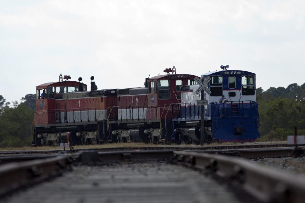 CAPE CANAVERAL, Fla. – Three NASA railroad locomotives at Kennedy Space Center in Florida move toward Launch Complex 39 area's Rotation, Processing and Surge Facility, or RPSF. The operation was to allow wheel and axle assemblies to be swapped between two of the locomotives. The RPSF was built to support work on the solid rocket used motors during the space shuttle era. The facility had never previously been used for another purpose, but is now free to serve other customers. With rails running into the building's high bay and a pair of heavy-lift cranes positioned overhead, the facility's capabilities were a perfect fit for the NASA Railroad's needs. Railroad managers wanted to trade the wheel and axle assemblies, or trucks, of locomotives No. 2 and No. 3. Locomotive No. 3 was painstakingly restored in recent years by the NASA Railroad team, and handles much of the rail work required at the center in the post-shuttle era. But the trucks on locomotive No. 2 are in better shape and are more environmentally friendly. For more information, visit: http://www.nasa.gov/exploration/systems/ground/rpsf_locomotives.html Photo credit: NASA/Jim Grossmann