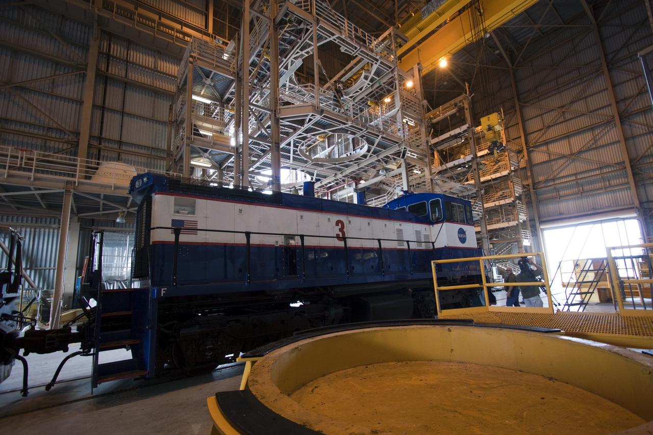 CAPE CANAVERAL, Fla. – A NASA railroad locomotive at Kennedy Space Center in Florida moves into Launch Complex 39 area's Rotation, Processing and Surge Facility, or RPSF. The operation was to allow wheel and axle assemblies to be swapped between two locomotives. The RPSF was built to support work on the solid rocket used motors during the space shuttle era. The facility had never previously been used for another purpose, but is now free to serve other customers. With rails running into the building's high bay and a pair of heavy-lift cranes positioned overhead, the facility's capabilities were a perfect fit for the NASA Railroad's needs. Railroad managers wanted to trade the wheel and axle assemblies, or trucks, of locomotives No. 2 and No. 3. Locomotive No. 3 was painstakingly restored in recent years by the NASA Railroad team, and handles much of the rail work required at the center in the post-shuttle era. But the trucks on locomotive No. 2 are in better shape and are more environmentally friendly. For more information, visit: http://www.nasa.gov/exploration/systems/ground/rpsf_locomotives.html Photo credit: NASA/Jim Grossmann