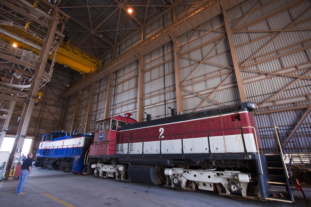 CAPE CANAVERAL, Fla. – Two NASA railroad locomotives at Kennedy Space Center in Florida move into Launch Complex 39 area's Rotation, Processing and Surge Facility, or RPSF. The operation was to allow wheel and axle assemblies to be swapped between locomotives. The RPSF was built to support work on the solid rocket used motors during the space shuttle era. The facility had never previously been used for another purpose, but is now free to serve other customers. With rails running into the building's high bay and a pair of heavy-lift cranes positioned overhead, the facility's capabilities were a perfect fit for the NASA Railroad's needs. Railroad managers wanted to trade the wheel and axle assemblies, or trucks, of locomotives No. 2 and No. 3. Locomotive No. 3 was painstakingly restored in recent years by the NASA Railroad team, and handles much of the rail work required at the center in the post-shuttle era. But the trucks on locomotive No. 2 are in better shape and are more environmentally friendly. For more information, visit: http://www.nasa.gov/exploration/systems/ground/rpsf_locomotives.html Photo credit: NASA/Jim Grossmann