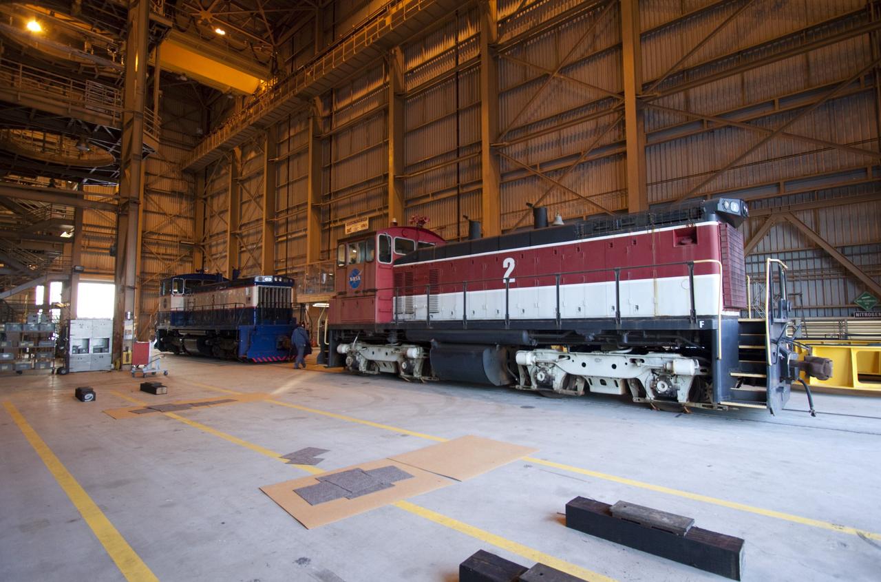 CAPE CANAVERAL, Fla. – Two NASA railroad locomotives at Kennedy Space Center in Florida move into Launch Complex 39 area's Rotation, Processing and Surge Facility, or RPSF. The operation was to allow wheel and axle assemblies to be swapped between locomotives. The RPSF was built to support work on the solid rocket used motors during the space shuttle era. The facility had never previously been used for another purpose, but is now free to serve other customers. With rails running into the building's high bay and a pair of heavy-lift cranes positioned overhead, the facility's capabilities were a perfect fit for the NASA Railroad's needs. Railroad managers wanted to trade the wheel and axle assemblies, or trucks, of locomotives No. 2 and No. 3. Locomotive No. 3 was painstakingly restored in recent years by the NASA Railroad team, and handles much of the rail work required at the center in the post-shuttle era. But the trucks on locomotive No. 2 are in better shape and are more environmentally friendly. For more information, visit: http://www.nasa.gov/exploration/systems/ground/rpsf_locomotives.html Photo credit: NASA/Jim Grossmann