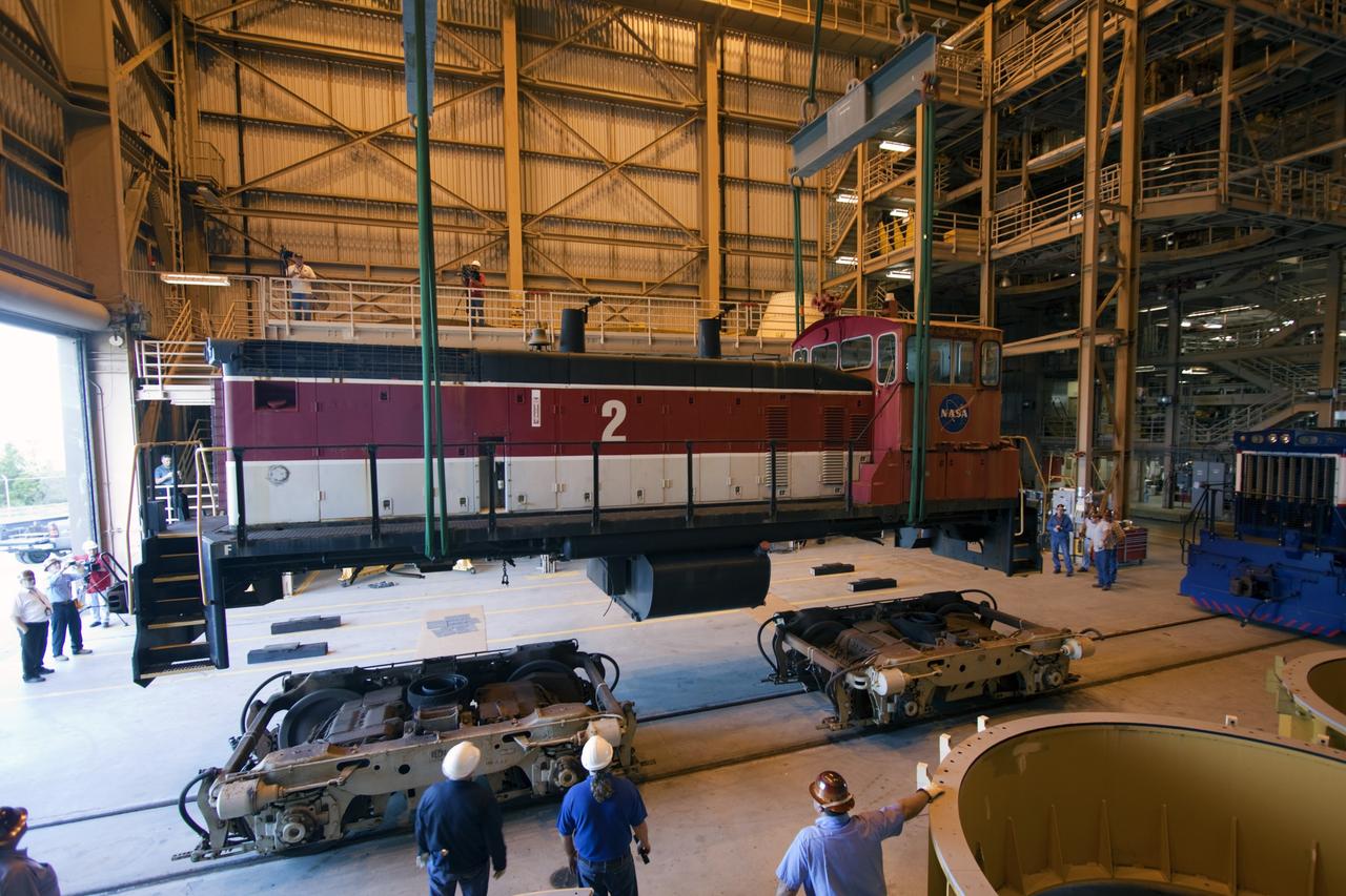 CAPE CANAVERAL, Fla. – Inside the Rotation, Processing and Surge Facility, or RPSF, at the Kennedy Space Center in Florida, an overhead crane lifts NASA locomotive No. 2 off of its trucks to be moved aside, clearing the way for locomotive No. 3 to be raised off its trucks and moved into position atop the trucks previously used by locomotive No. 2. The RPSF was built to support work on the solid rocket used motors during the space shuttle era. The facility had never previously been used for another purpose, but is now free to serve other customers. With rails running into the building's high bay and a pair of heavy-lift cranes positioned overhead, the facility's capabilities were a perfect fit for the NASA Railroad's needs. Railroad managers wanted to trade the wheel and axle assemblies, or trucks, of locomotives No. 2 and No. 3. Locomotive No. 3 was painstakingly restored in recent years by the NASA Railroad team, and handles much of the rail work required at the center in the post-shuttle era. But the trucks on locomotive No. 2 are in better shape and are more environmentally friendly. For more information, visit: http://www.nasa.gov/exploration/systems/ground/rpsf_locomotives.html Photo credit: NASA/Jim Grossmann
