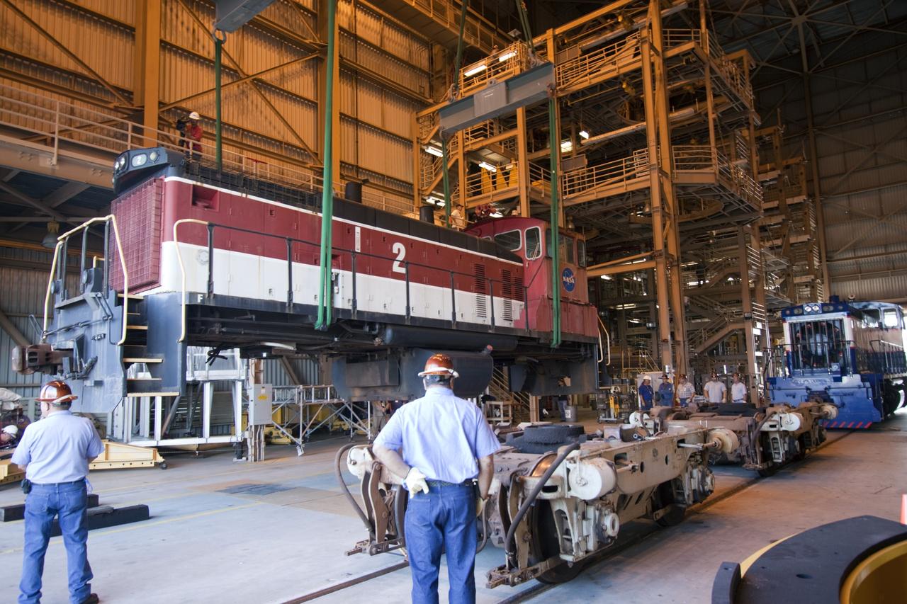 CAPE CANAVERAL, Fla. – Inside the Rotation, Processing and Surge Facility, or RPSF, at the Kennedy Space Center in Florida, an overhead crane lifts NASA locomotive No. 2 off of its trucks to be moved aside, clearing the way for locomotive No. 3 to be raised off its trucks and moved into position atop the trucks previously used by locomotive No. 2. The RPSF was built to support work on the solid rocket used motors during the space shuttle era. The facility had never previously been used for another purpose, but is now free to serve other customers. With rails running into the building's high bay and a pair of heavy-lift cranes positioned overhead, the facility's capabilities were a perfect fit for the NASA Railroad's needs. Railroad managers wanted to trade the wheel and axle assemblies, or trucks, of locomotives No. 2 and No. 3. Locomotive No. 3 was painstakingly restored in recent years by the NASA Railroad team, and handles much of the rail work required at the center in the post-shuttle era. But the trucks on locomotive No. 2 are in better shape and are more environmentally friendly. For more information, visit: http://www.nasa.gov/exploration/systems/ground/rpsf_locomotives.html Photo credit: NASA/Jim Grossmann