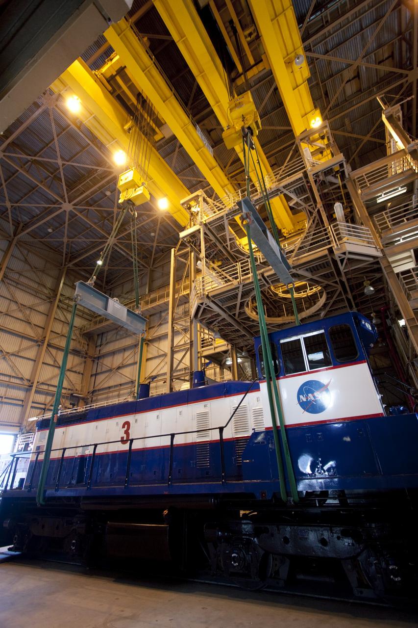 CAPE CANAVERAL, Fla. – Inside the Rotation, Processing and Surge Facility, or RPSF, at the Kennedy Space Center in Florida, an overhead crane lifts NASA locomotive No. 3 off of its trucks to be moved into position atop the trucks previously used by locomotive No. 2. The RPSF was built to support work on the solid rocket used motors during the space shuttle era. The facility had never previously been used for another purpose, but is now free to serve other customers. With rails running into the building's high bay and a pair of heavy-lift cranes positioned overhead, the facility's capabilities were a perfect fit for the NASA Railroad's needs. Railroad managers wanted to trade the wheel and axle assemblies, or trucks, of locomotives No. 2 and No. 3. Locomotive No. 3 was painstakingly restored in recent years by the NASA Railroad team, and handles much of the rail work required at the center in the post-shuttle era. But the trucks on locomotive No. 2 are in better shape and are more environmentally friendly. For more information, visit: http://www.nasa.gov/exploration/systems/ground/rpsf_locomotives.html Photo credit: NASA/Jim Grossmann