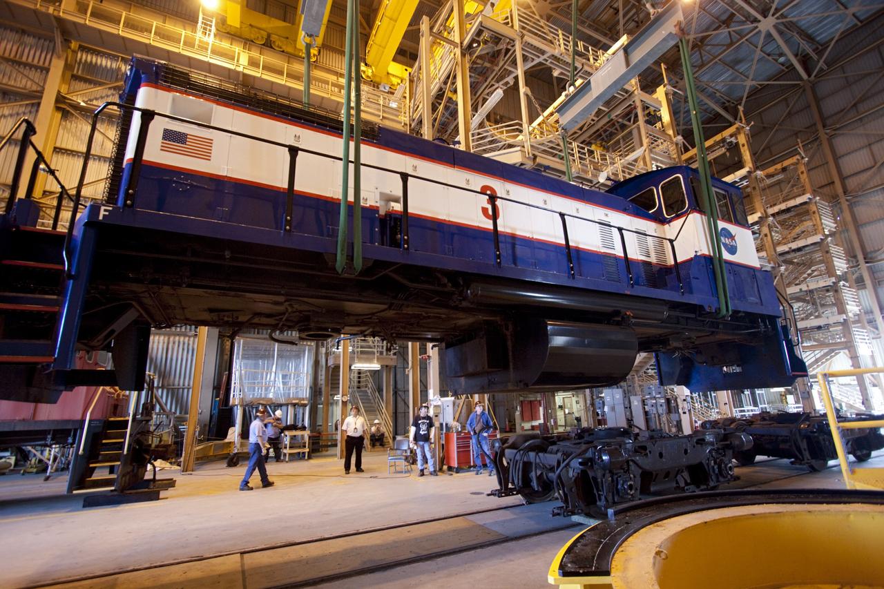 CAPE CANAVERAL, Fla. – Inside the Rotation, Processing and Surge Facility, or RPSF, at the Kennedy Space Center in Florida, an overhead crane lifts NASA locomotive No. 3 off of its trucks to be moved into position atop the trucks previously used by locomotive No. 2. The RPSF was built to support work on the solid rocket used motors during the space shuttle era. The facility had never previously been used for another purpose, but is now free to serve other customers. With rails running into the building's high bay and a pair of heavy-lift cranes positioned overhead, the facility's capabilities were a perfect fit for the NASA Railroad's needs. Railroad managers wanted to trade the wheel and axle assemblies, or trucks, of locomotives No. 2 and No. 3. Locomotive No. 3 was painstakingly restored in recent years by the NASA Railroad team, and handles much of the rail work required at the center in the post-shuttle era. But the trucks on locomotive No. 2 are in better shape and are more environmentally friendly. For more information, visit: http://www.nasa.gov/exploration/systems/ground/rpsf_locomotives.html Photo credit: NASA/Jim Grossmann