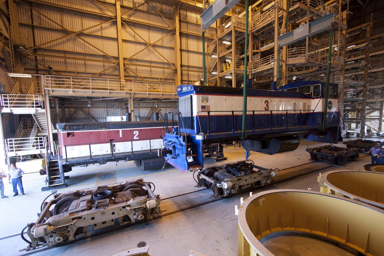 CAPE CANAVERAL, Fla. – Inside the Rotation, Processing and Surge Facility, or RPSF, at the Kennedy Space Center in Florida, an overhead crane lifts NASA locomotive No. 3 off of its trucks to be moved into position atop the trucks previously used by locomotive No. 2. The RPSF was built to support work on the solid rocket used motors during the space shuttle era. The facility had never previously been used for another purpose, but is now free to serve other customers. With rails running into the building's high bay and a pair of heavy-lift cranes positioned overhead, the facility's capabilities were a perfect fit for the NASA Railroad's needs. Railroad managers wanted to trade the wheel and axle assemblies, or trucks, of locomotives No. 2 and No. 3. Locomotive No. 3 was painstakingly restored in recent years by the NASA Railroad team, and handles much of the rail work required at the center in the post-shuttle era. But the trucks on locomotive No. 2 are in better shape and are more environmentally friendly. For more information, visit: http://www.nasa.gov/exploration/systems/ground/rpsf_locomotives.html Photo credit: NASA/Jim Grossmann
