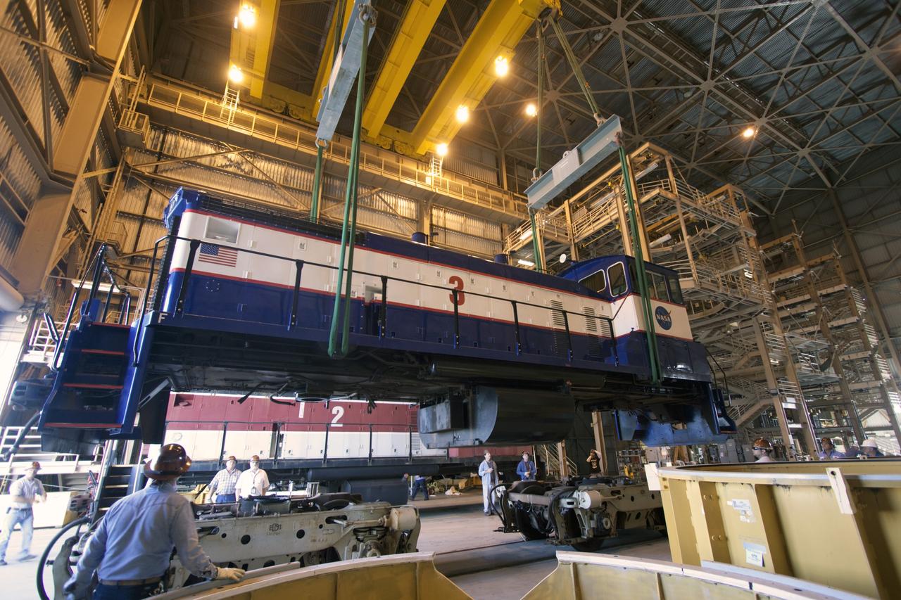 CAPE CANAVERAL, Fla. – Inside the Rotation, Processing and Surge Facility, or RPSF, at the Kennedy Space Center in Florida, an overhead crane lifts NASA locomotive No. 3 moving it into position atop the trucks previously used by locomotive No. 2. The RPSF was built to support work on the solid rocket used motors during the space shuttle era. The facility had never previously been used for another purpose, but is now free to serve other customers. With rails running into the building's high bay and a pair of heavy-lift cranes positioned overhead, the facility's capabilities were a perfect fit for the NASA Railroad's needs. Railroad managers wanted to trade the wheel and axle assemblies, or trucks, of locomotives No. 2 and No. 3. Locomotive No. 3 was painstakingly restored in recent years by the NASA Railroad team, and handles much of the rail work required at the center in the post-shuttle era. But the trucks on locomotive No. 2 are in better shape and are more environmentally friendly. For more information, visit: http://www.nasa.gov/exploration/systems/ground/rpsf_locomotives.html Photo credit: NASA/Jim Grossmann