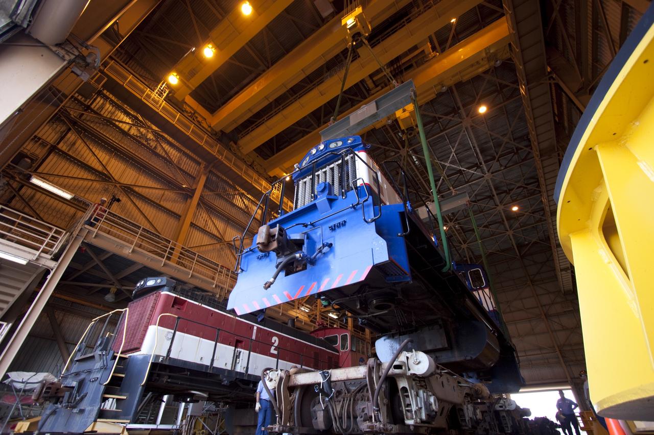 CAPE CANAVERAL, Fla. – Inside the Rotation, Processing and Surge Facility, or RPSF, at the Kennedy Space Center in Florida, an overhead crane lifts NASA locomotive No. 3 moving it into position atop the trucks previously used by locomotive No. 2. The RPSF was built to support work on the solid rocket used motors during the space shuttle era. The facility had never previously been used for another purpose, but is now free to serve other customers. With rails running into the building's high bay and a pair of heavy-lift cranes positioned overhead, the facility's capabilities were a perfect fit for the NASA Railroad's needs. Railroad managers wanted to trade the wheel and axle assemblies, or trucks, of locomotives No. 2 and No. 3. Locomotive No. 3 was painstakingly restored in recent years by the NASA Railroad team, and handles much of the rail work required at the center in the post-shuttle era. But the trucks on locomotive No. 2 are in better shape and are more environmentally friendly. For more information, visit: http://www.nasa.gov/exploration/systems/ground/rpsf_locomotives.html Photo credit: NASA/Jim Grossmann