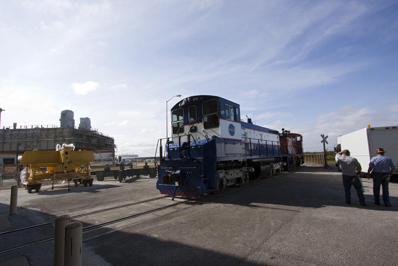 CAPE CANAVERAL, Fla. – NASA locomotive No. 1 pulls locomotive No. 3 out of the Rotation, Processing and Surge Facility, or RPSF, at the Kennedy Space Center in Florida. Inside, an overhead crane was used to lift NASA locomotive No. 2 off of its trucks and moved aside, so locomotive No. 3 could be raised off its trucks and moved into position atop the trucks previously used by locomotive No. 2.      The RPSF was built to support work on the solid rocket used motors during the space shuttle era. The facility had never previously been used for another purpose, but is now free to serve other customers. With rails running into the building's high bay and a pair of heavy-lift cranes positioned overhead, the facility's capabilities were a perfect fit for the NASA Railroad's needs. Railroad managers wanted to trade the wheel and axle assemblies, or trucks, of locomotives No. 2 and No. 3. Locomotive No. 3 was painstakingly restored in recent years by the NASA Railroad team, and handles much of the rail work required at the center in the post-shuttle era. But the trucks on locomotive No. 2 are in better shape and are more environmentally friendly. For more information, visit: http://www.nasa.gov/exploration/systems/ground/rpsf_locomotives.html Photo credit: NASA/Jim Grossmann